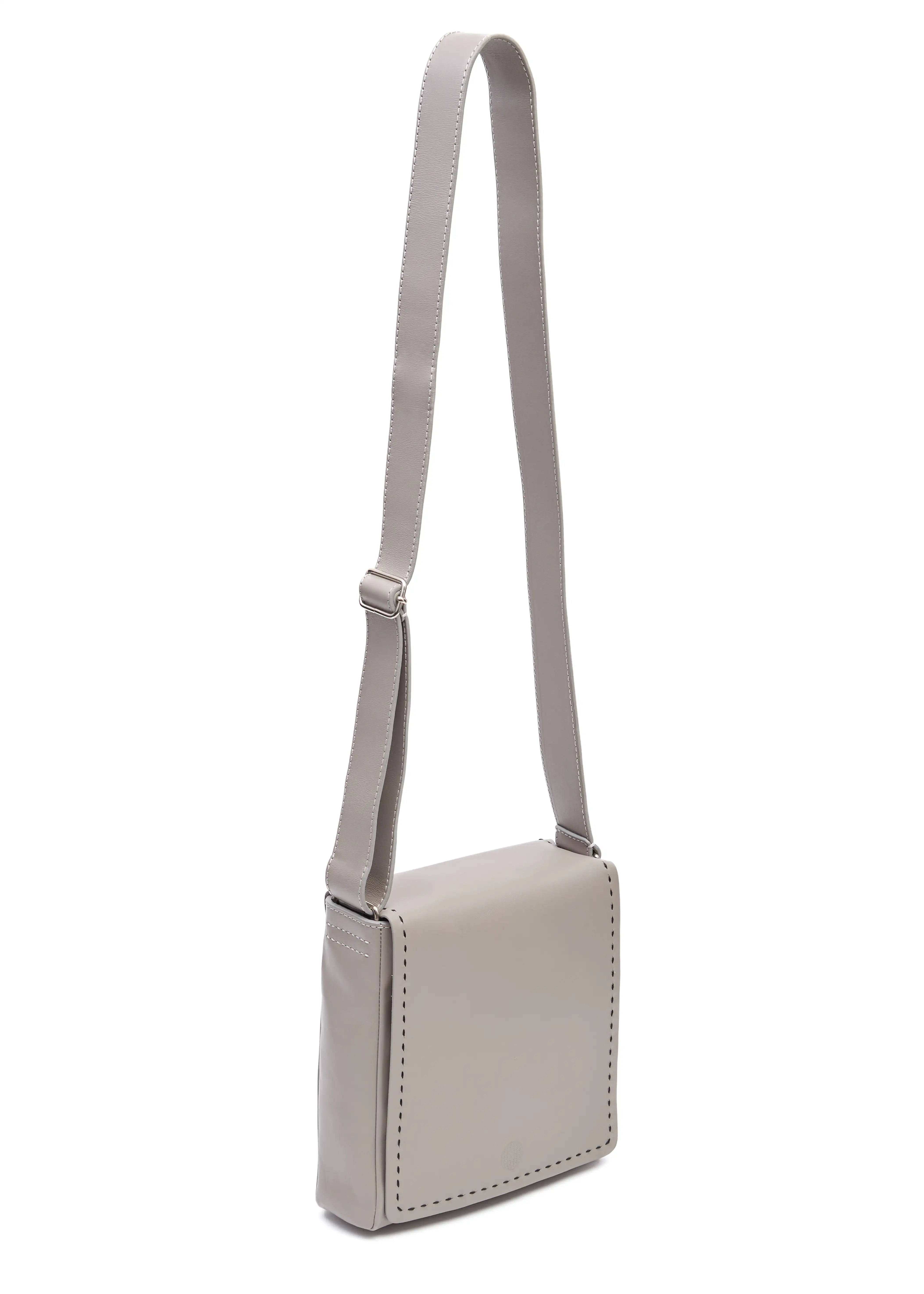 Side view of the Philini Anastasia Messenger Bag in taupe aniline nappa leather, square shape with full-flap front, perimeter stitching, and adjustable leather strap. Minimalist handcrafted leather crossbody bag for women.