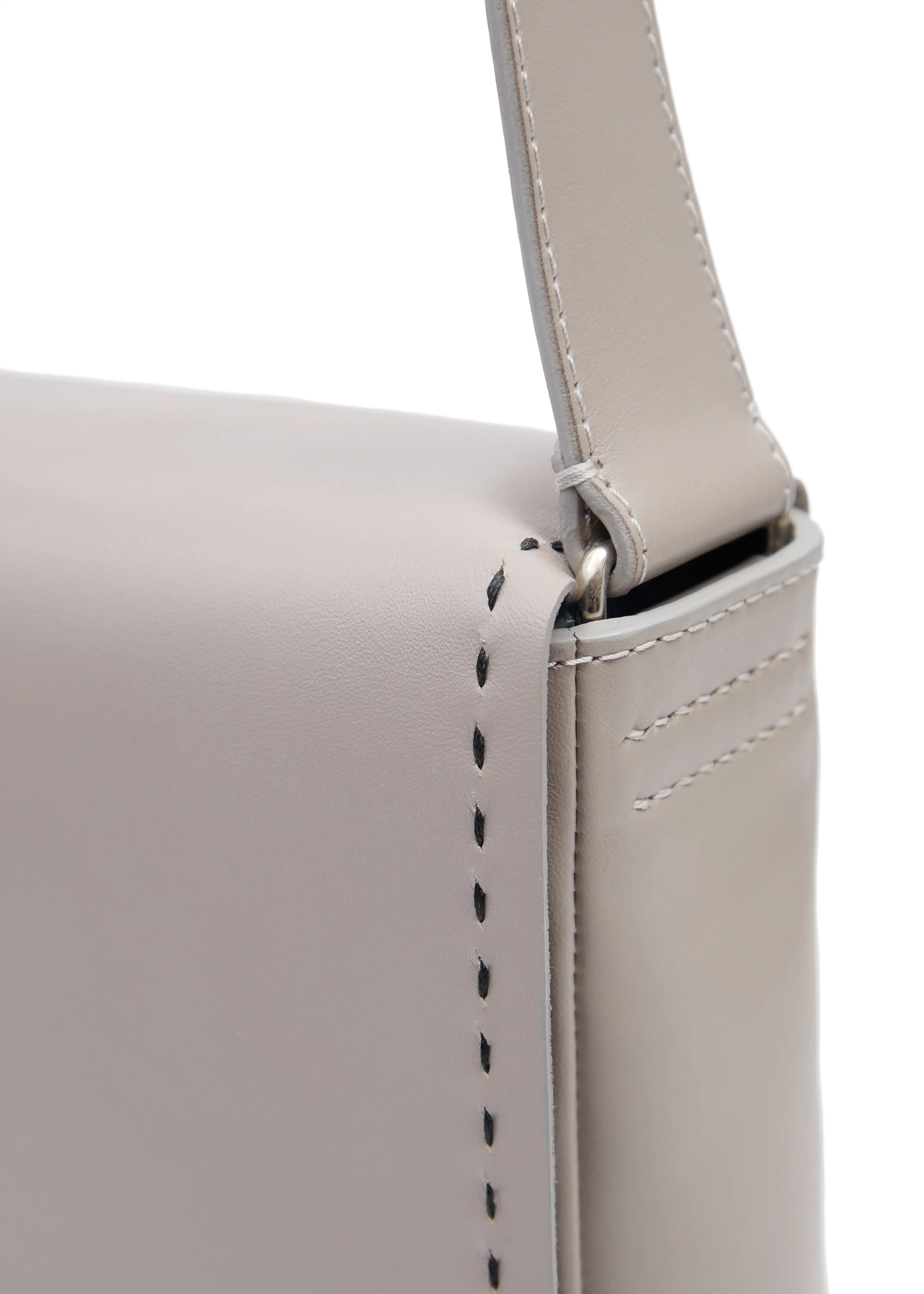 Close-up of Philini Anastasia Messenger Bag in taupe aniline nappa leather, showing black perimeter stitching, silver hardware on handle, and hand-stitched details. Premium structured leather purse for daily wear