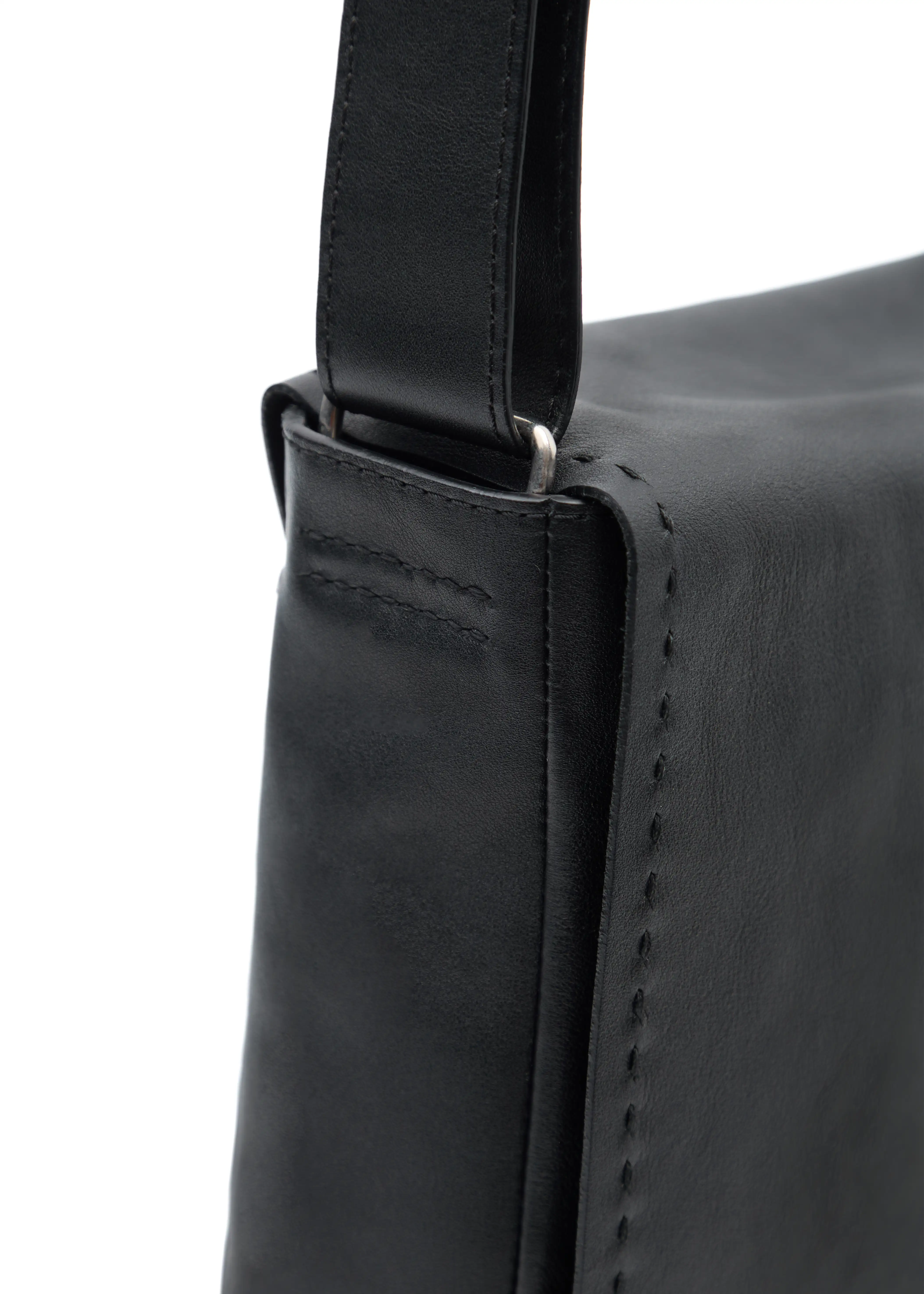 Close-up of Philini Anastasia Messenger Bag in black aniline nappa leather, showing black perimeter stitching, silver hardware on handle, and hand-stitched details. The handcrafted designer leather bag