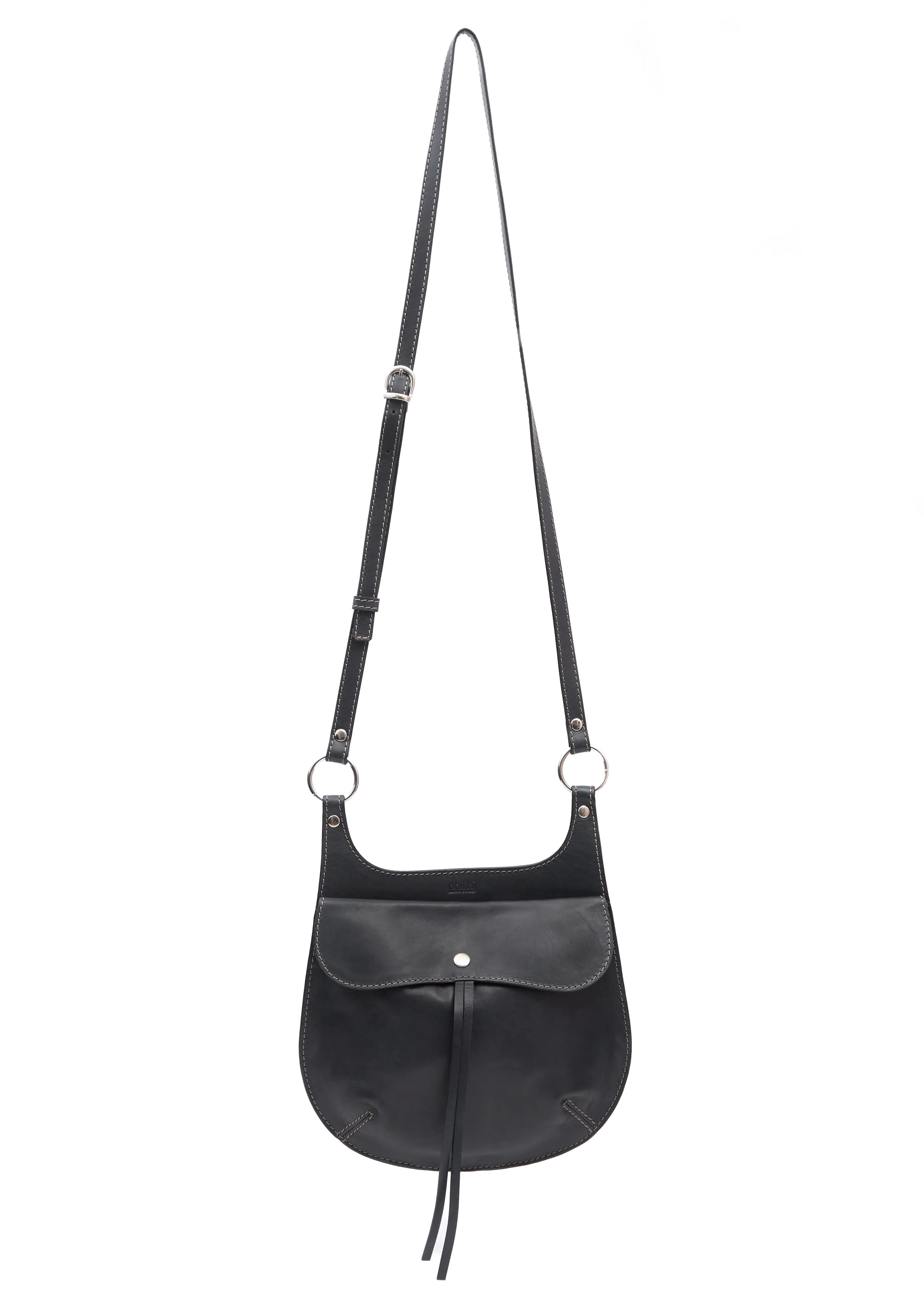 Front view of the Philini Cowboy Crossbody Bag in black calf leather, rounded saddle silhouette with front flap, snap closure, and long adjustable strap. Handcrafted artisanal leather crossbody