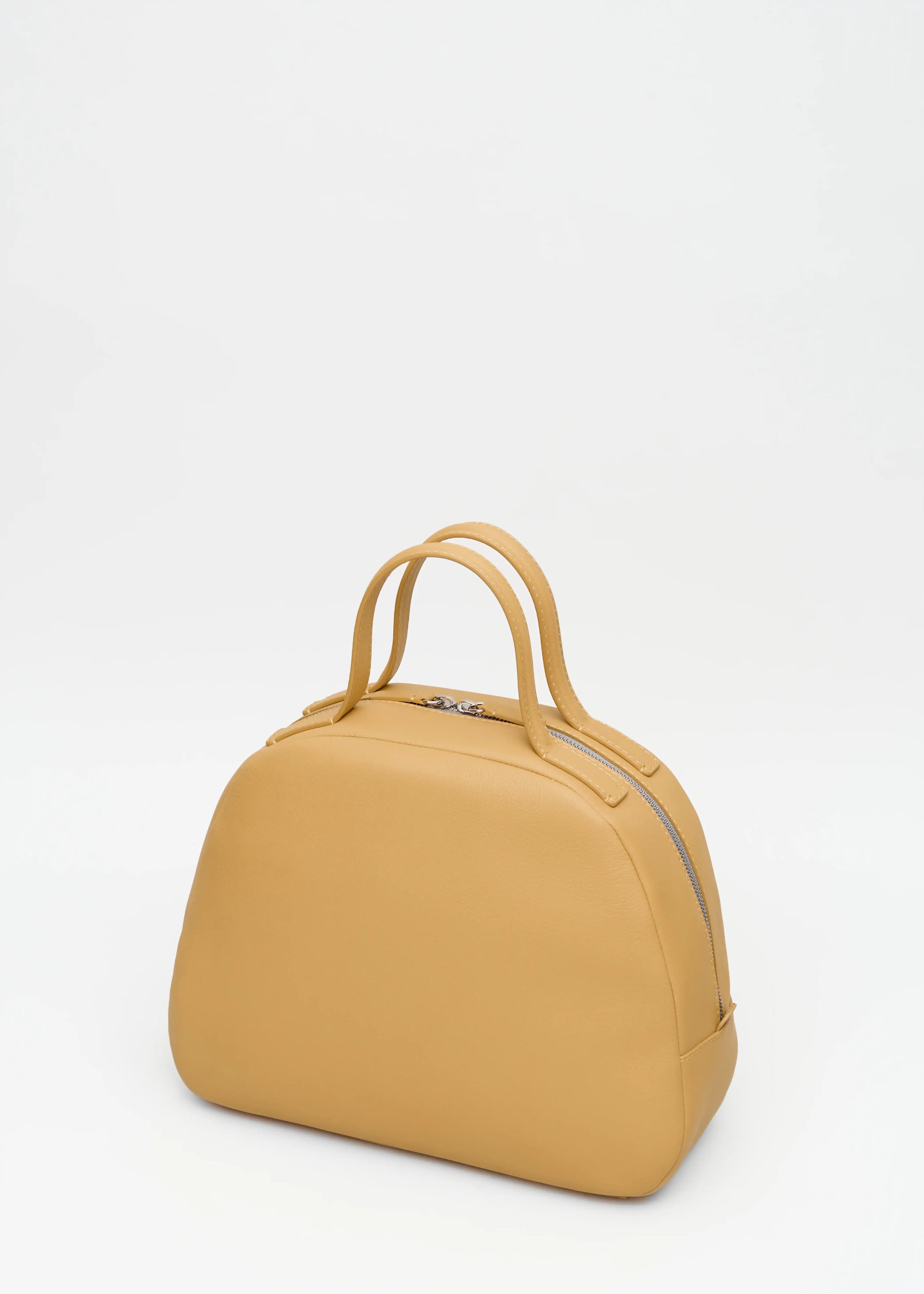 Back view of the Philini Domi Handbag in yellow nappa leather, featuring a dome shape, short handles, silver rivets, and zipper. Handmade leather bag with minimalist design