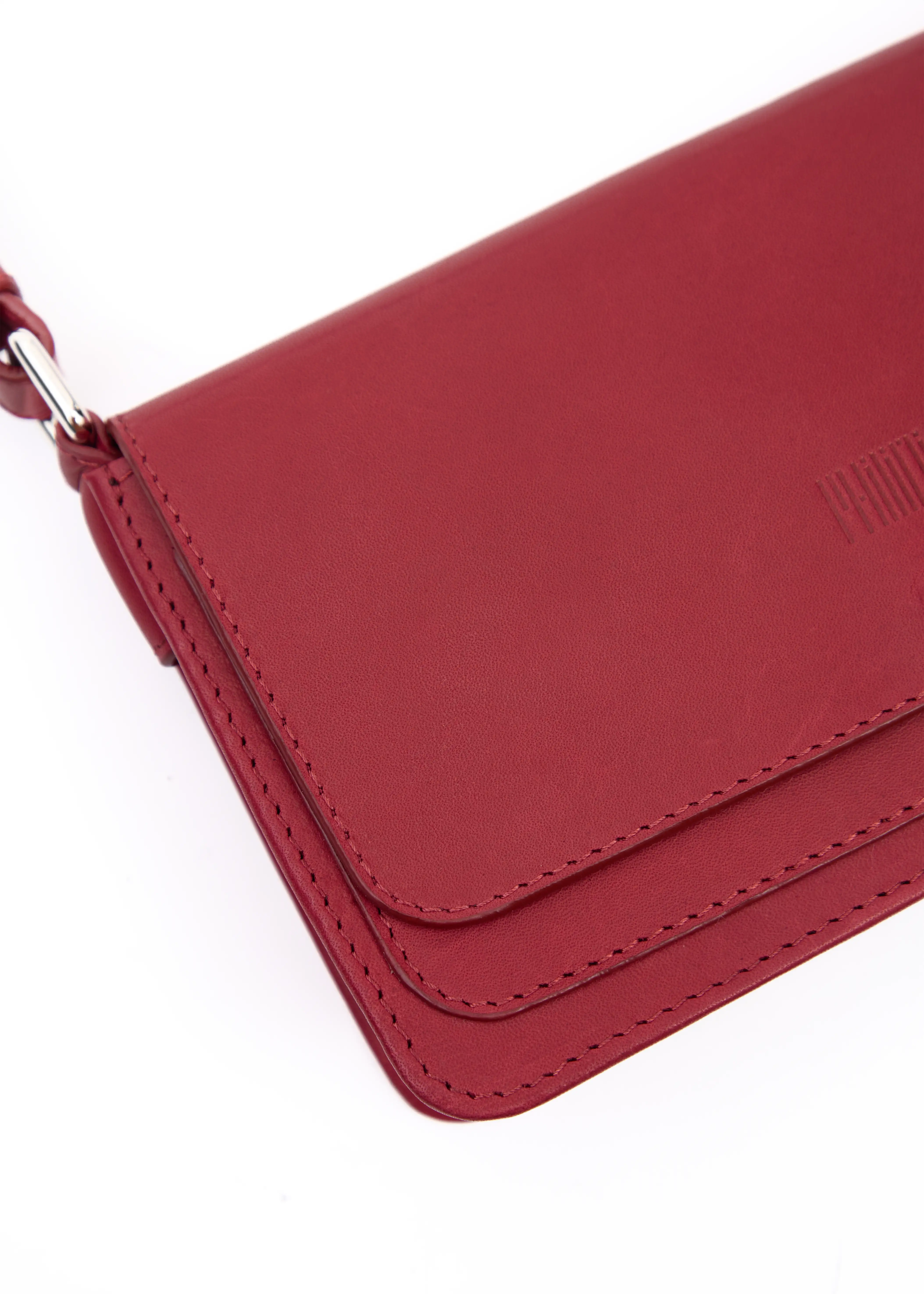 Close-up detail of the Philini Mihaela Wallet Bag in red Nappa leather, highlighting the soft textured finish, precise hand stitching, stamped logo, and silver cufflink closure. This wallet crossbody is a compact, designer leather essential.