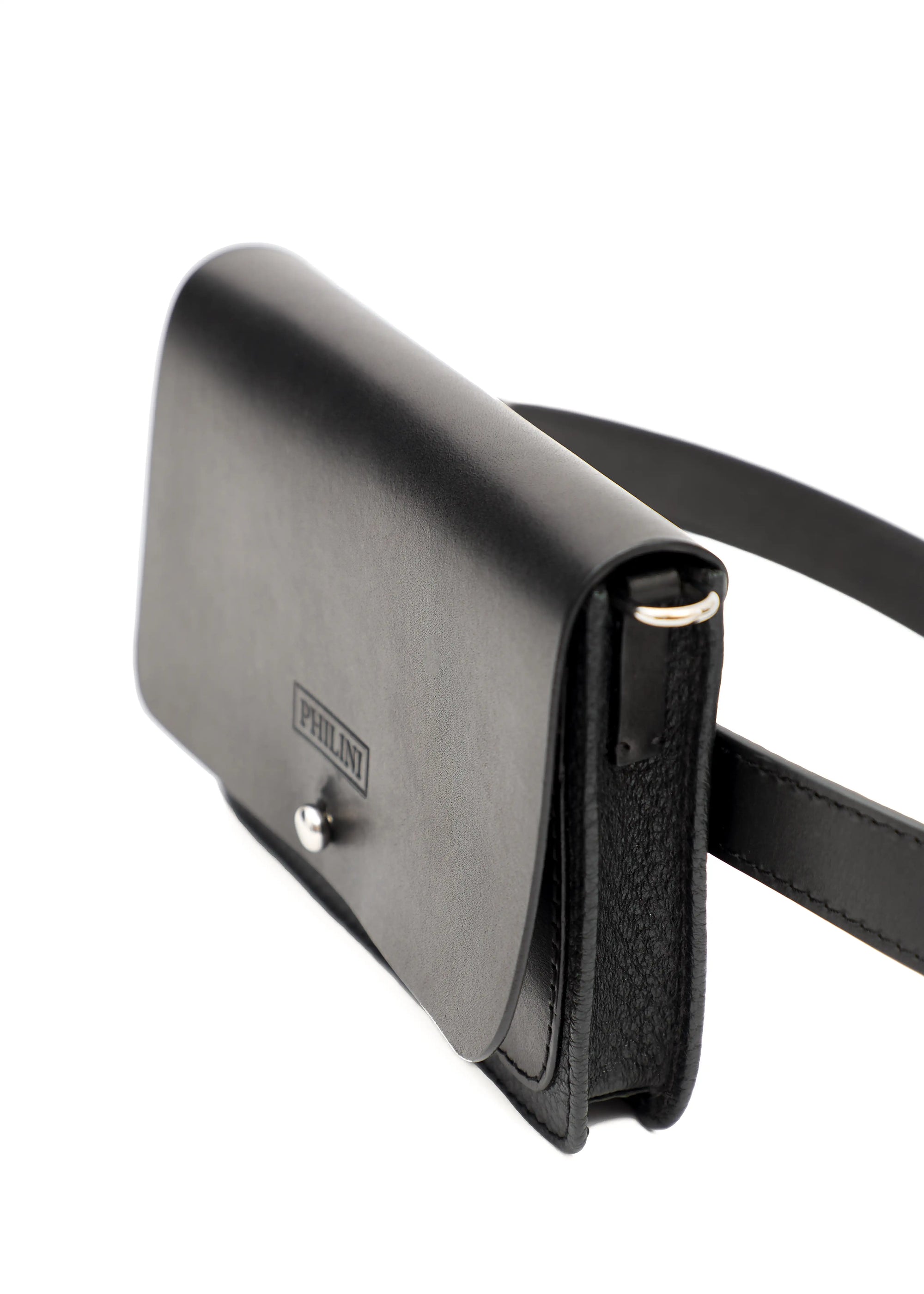 Small leather belt bag with a front flap made of calf leather and a cufflink closure. The sides feature silver detailing where the handle attaches to the carabiners