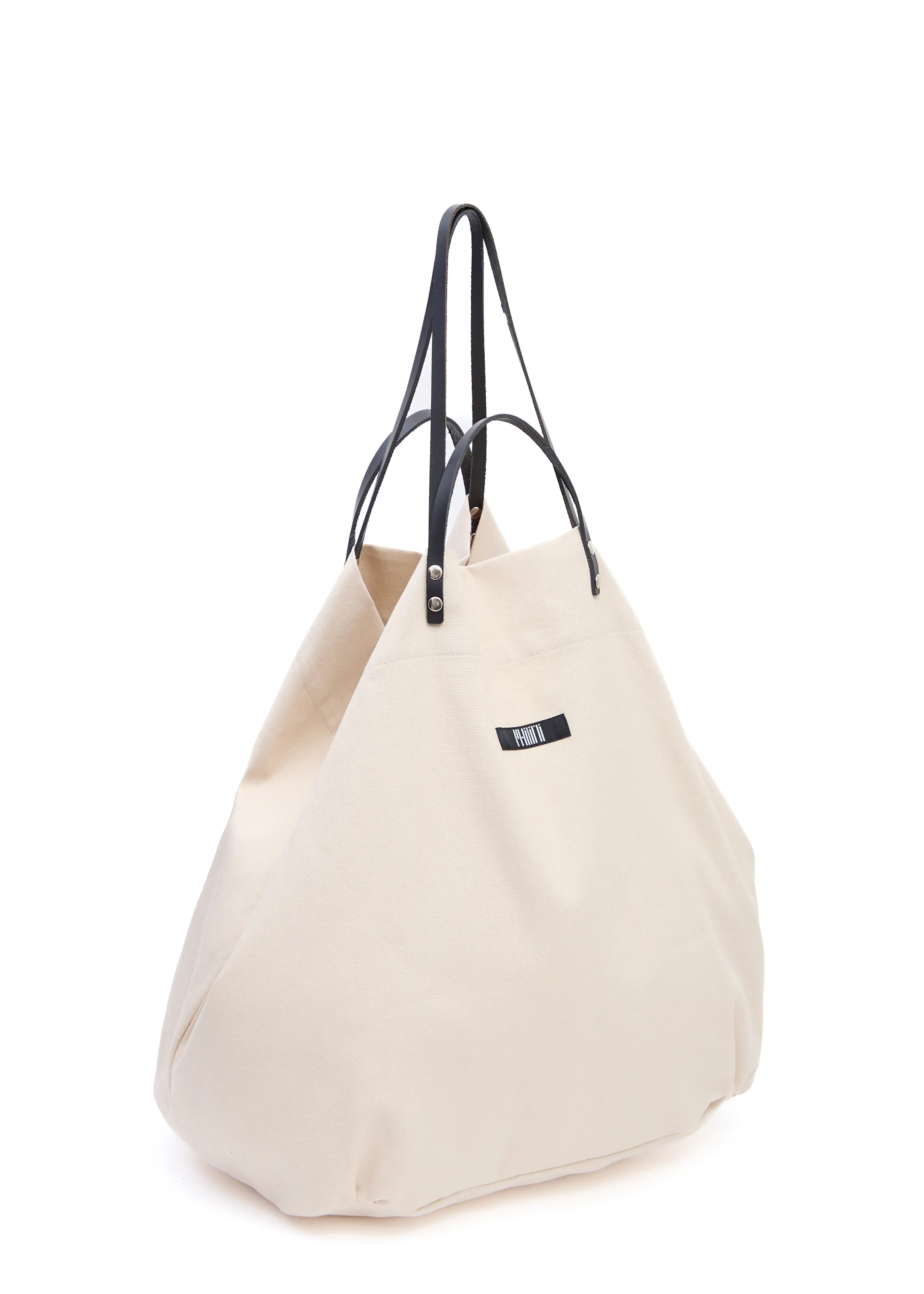 Side view of the Cream Philini Shopper in light cotton, with dual calf leather handles, silver-toned hardware, and a fabric logo. Stylish and minimalistic shopper