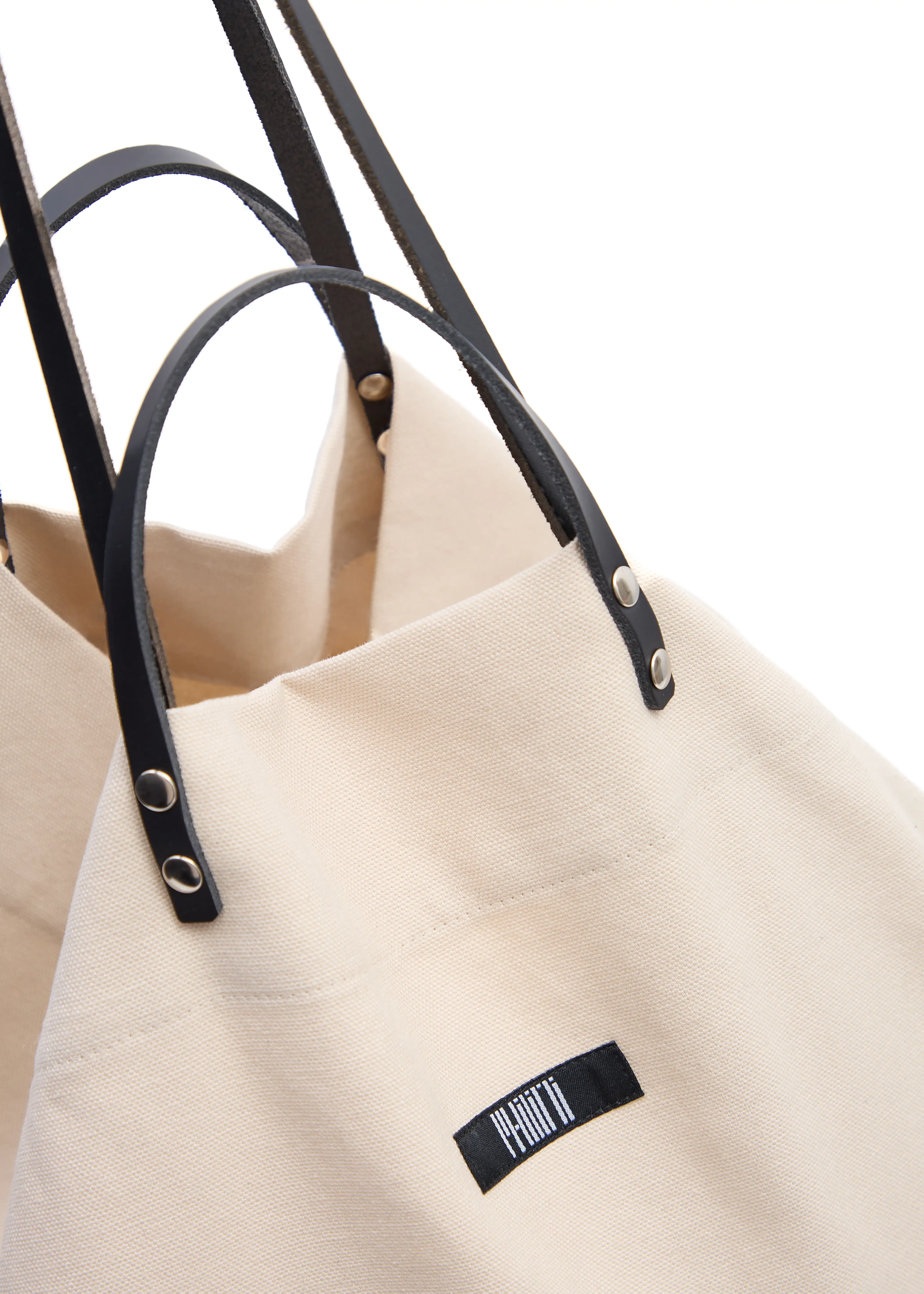Close-up of the Philini Cream Shopper, highlighting the soft cotton texture, double leather handle design with silver detailing, and secure top closure. A designed eco-friendly shopper, blending practicality and style