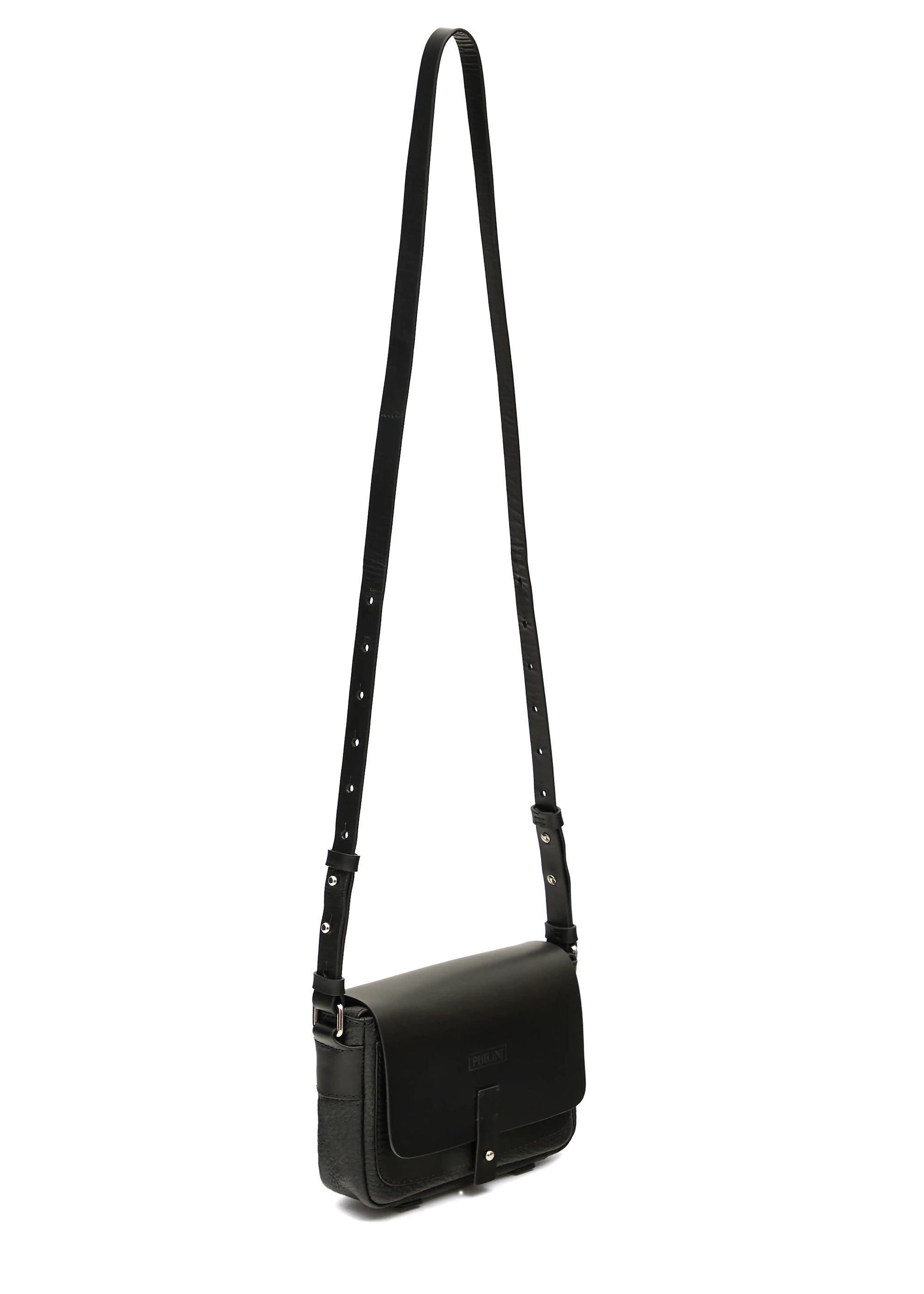 Side view of the Philini Whitney Black Leather Bag, a handcrafted designer bag with a rectangular shape, premium full-grain leather front flap, silver push-button closure, and an adjustable strap with silver accents. Designed in Germany from sustainable materials.