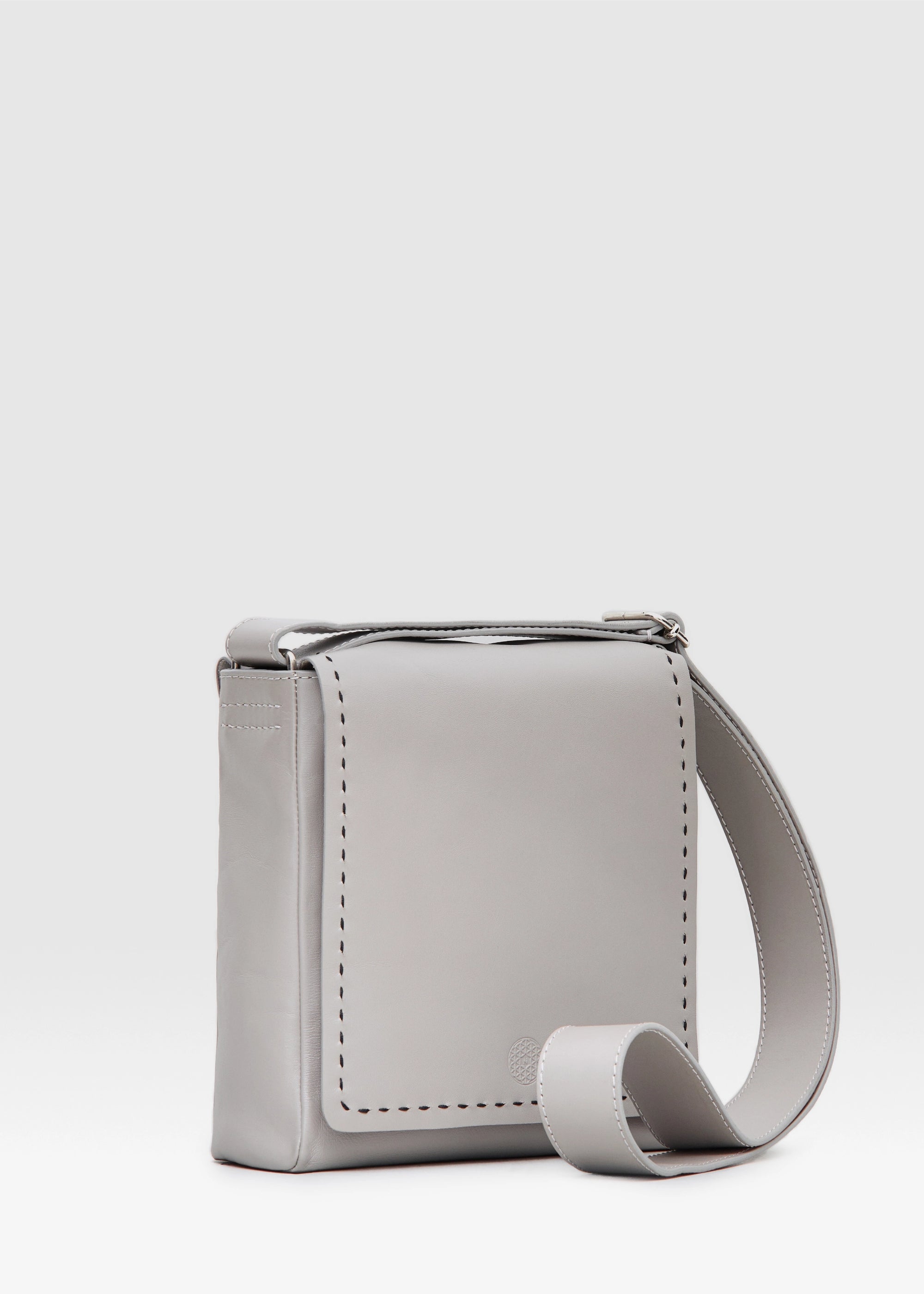 Side view of the Philini Anastasia Messenger Bag in taupe aniline nappa leather, square shape with full-flap front, perimeter stitching, and adjustable leather strap. Minimalist handcrafted leather crossbody bag for women.