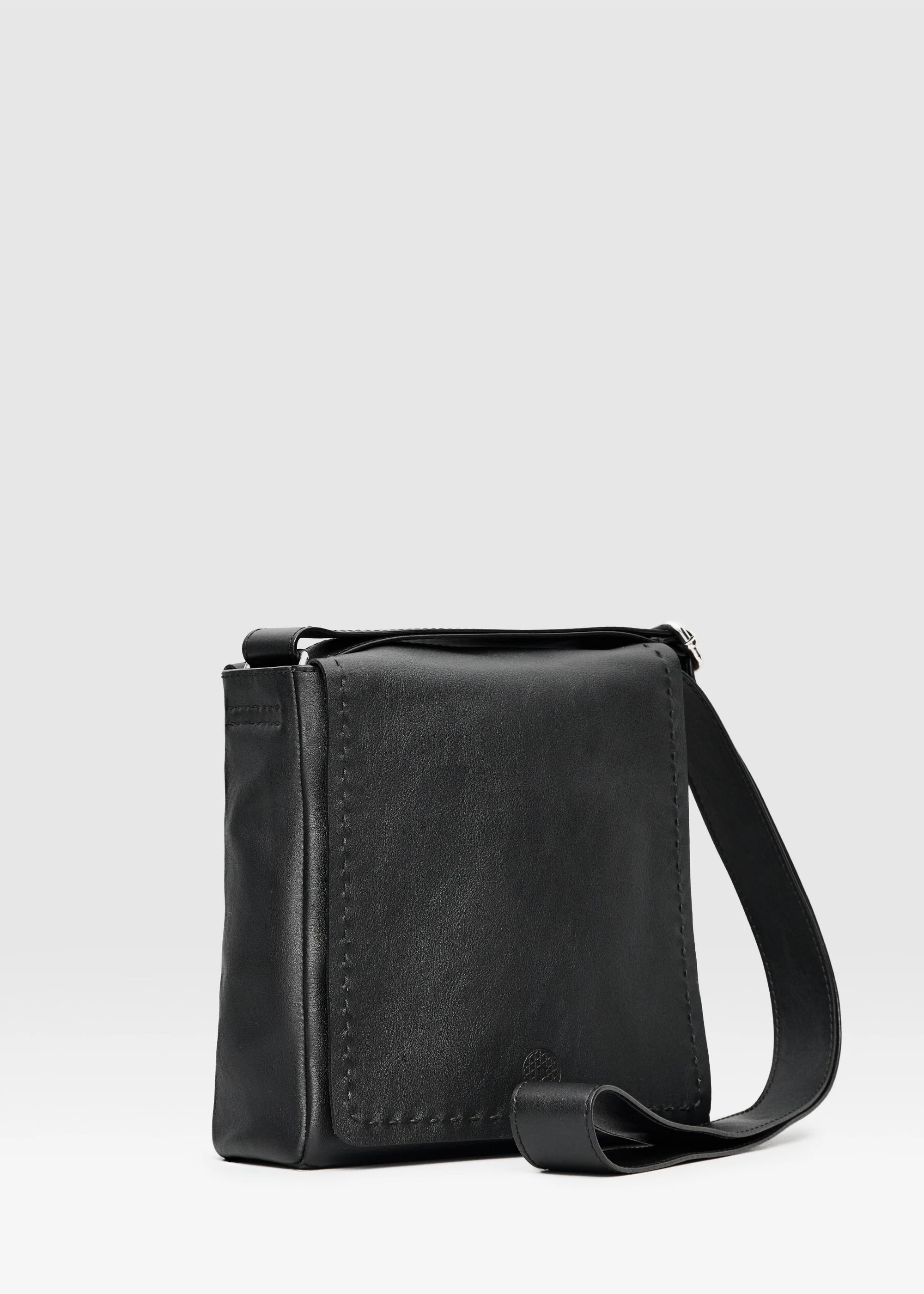 Side view of the Philini Anastasia Messenger Bag in black aniline nappa leather, featuring a structured square design, full front flap, and hand-stitches. Stylish black leather shoulder bag for everyday wear