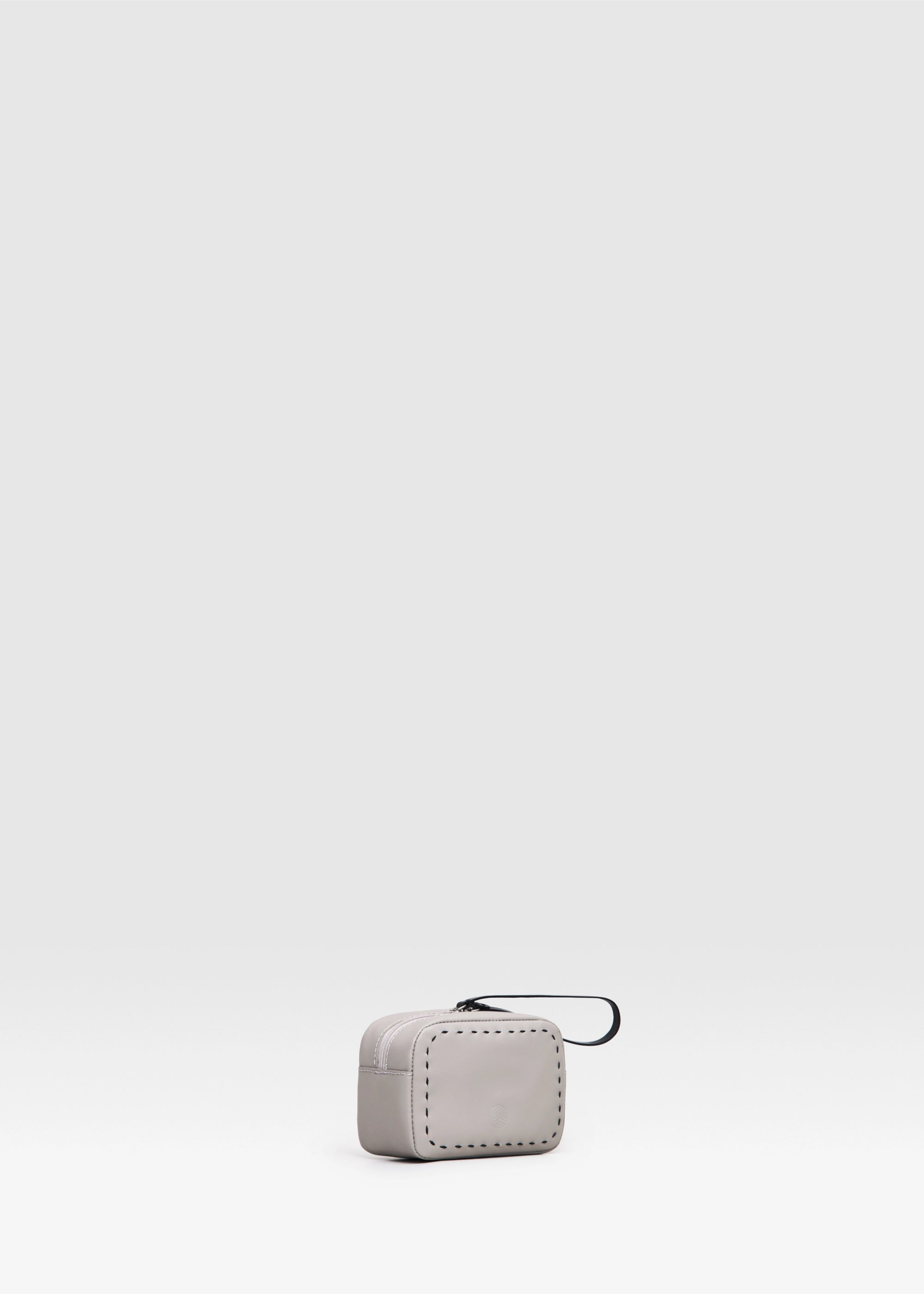 Side view of the Philini Anny taupe leather cosmetic bag, boxy silhouette with zip closure, leather pull, and hand-stitched details. Compact leather toiletry bag