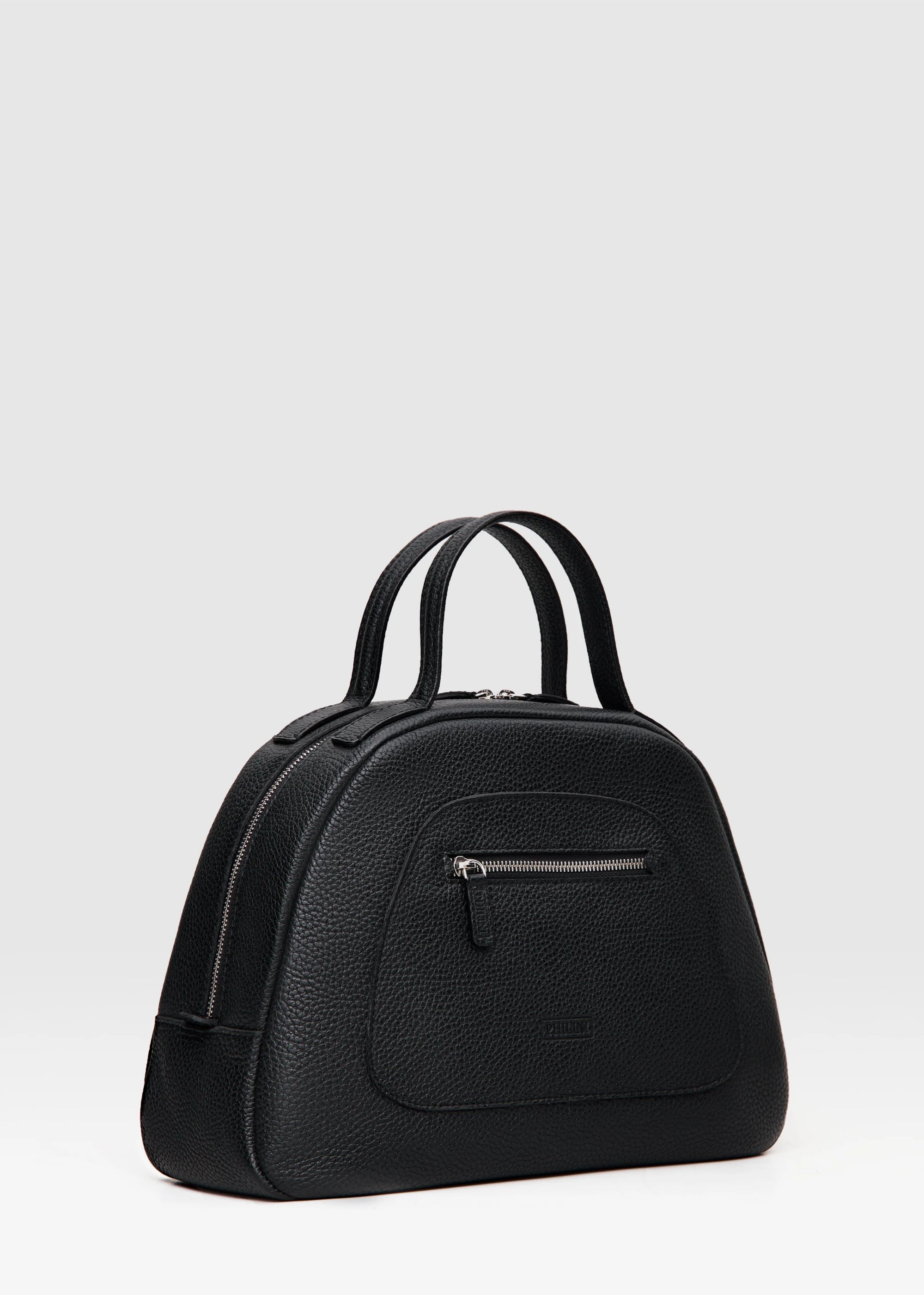 Side 3/4 view of the Philini Domi Black dome-shaped handbag, handcrafted from premium buffalo leather. Features include a front zip pocket, short handles, and silver rivet and zipper details. A sustainable, eco-conscious luxury accessory and timeless wardrobe essential.