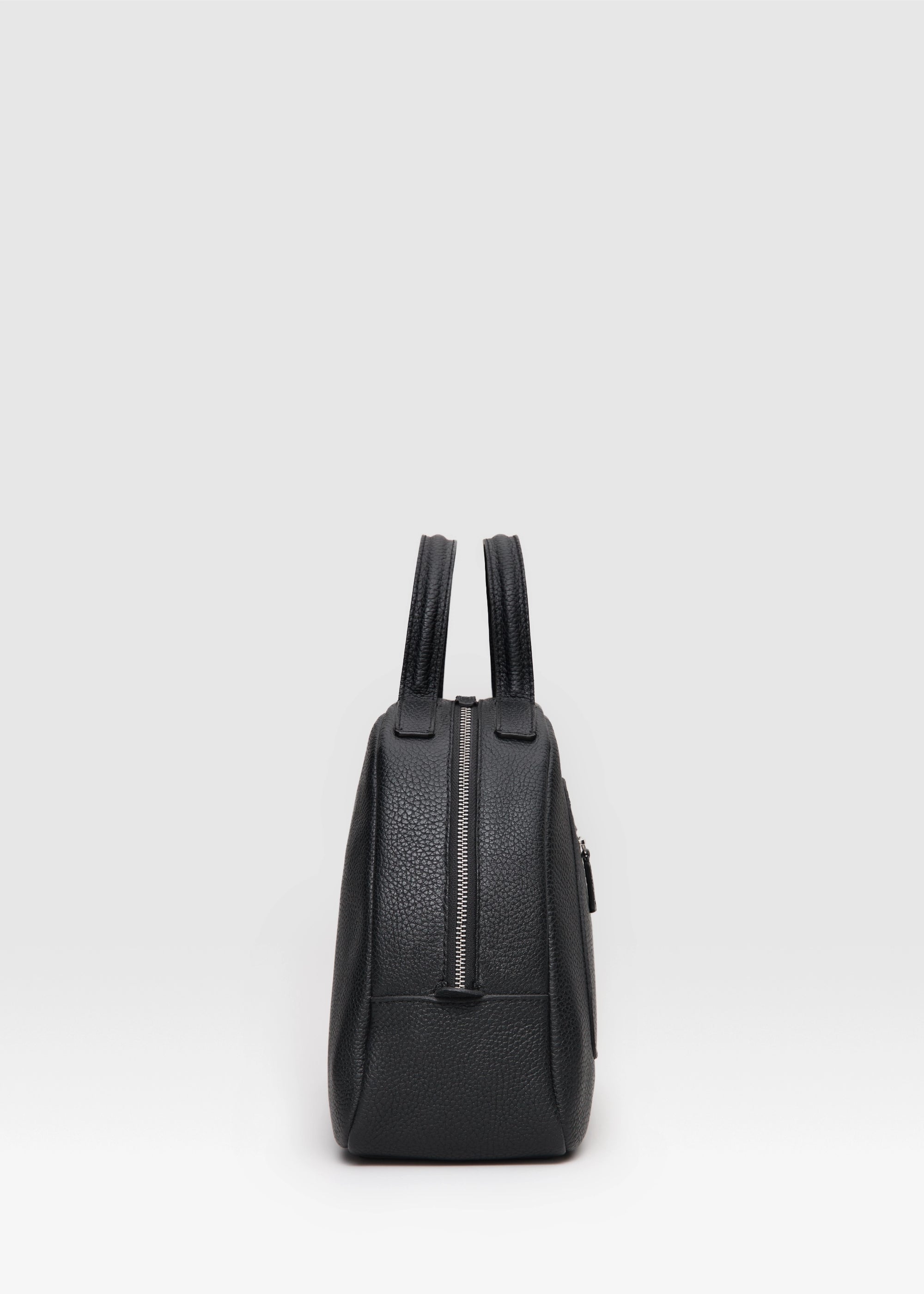 Profile view of the Philini Domi Black Dome Handbag, crafted from premium buffalo leather with four small leather pads as protective feet. This sustainable leather bag is a timeless accessory, ideal for minimalist style