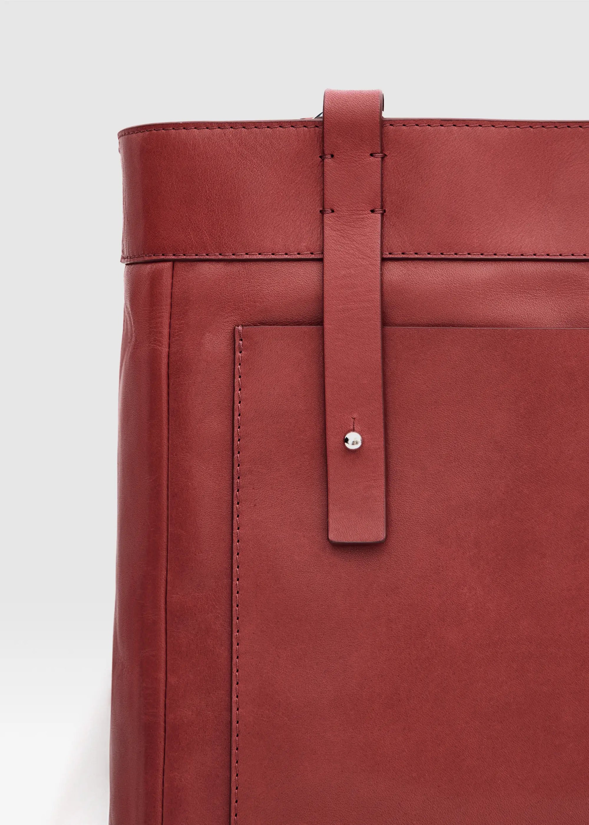 Detailed view of the Philini Elena Red Tote Bag in red aniline leather, featuring a leather exterior pocket and silver hoop accents on the handles.