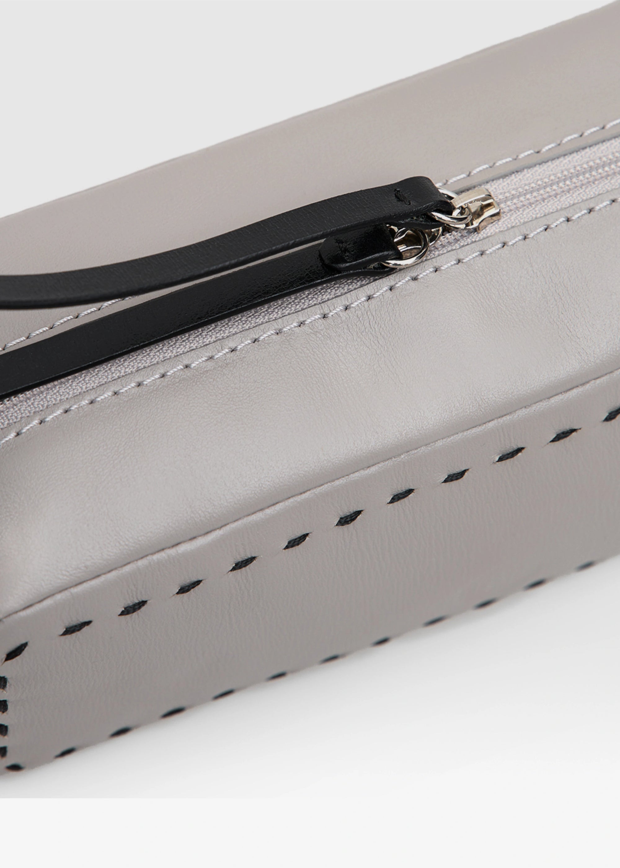 Close detail view of the Philini Ellie Cosmetic Bag in a compact rectangular shape, crafted from taupe aniline leather. Features a zip closure with a leather pull and hand-stitched finish. Minimalist leather makeup bag