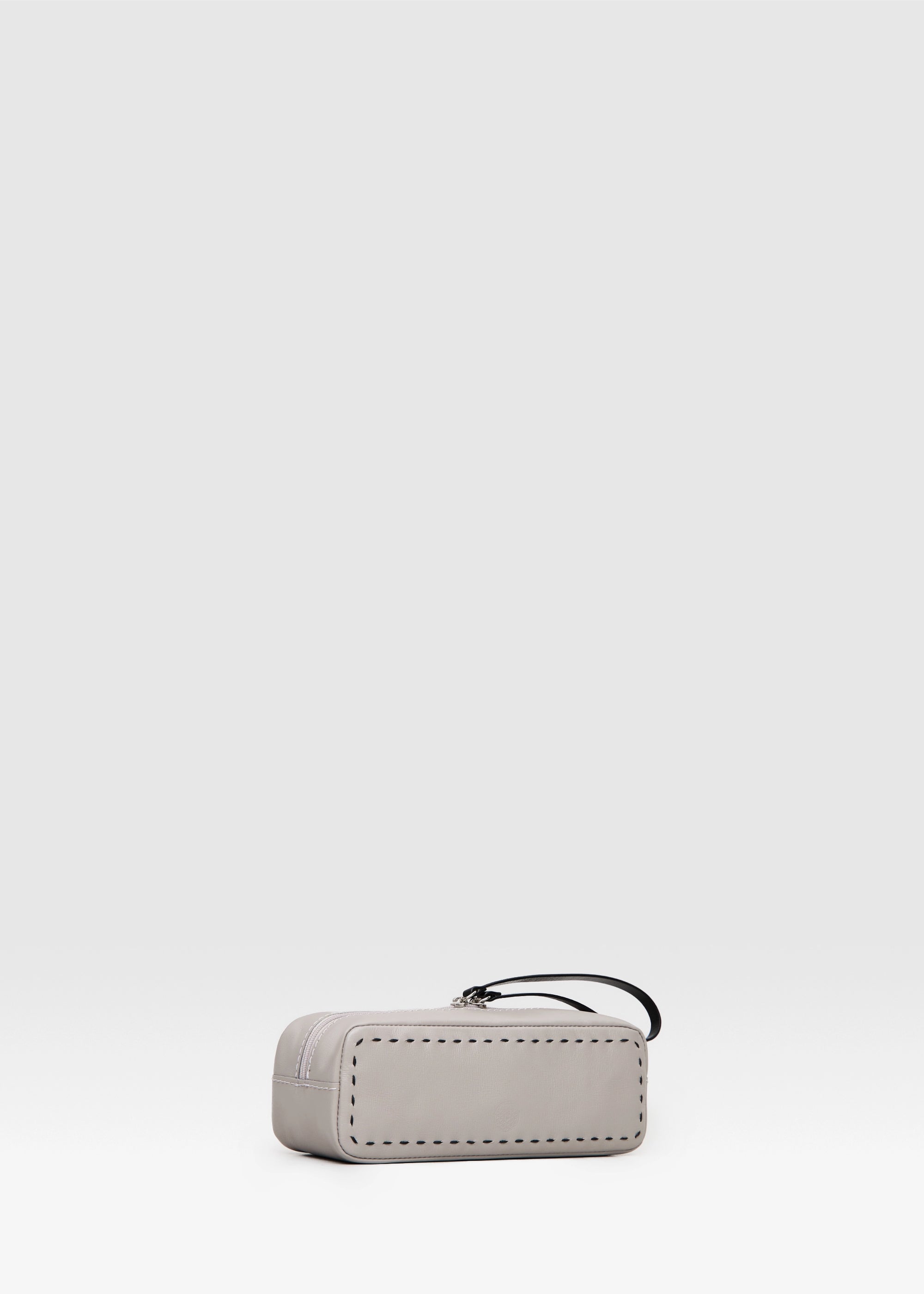 Side view of the Philini Ellie Cosmetic Bag in taupe aniline leather, showing hand-stitched details and zip closure with leather pull. Minimalist small leather makeup bag,