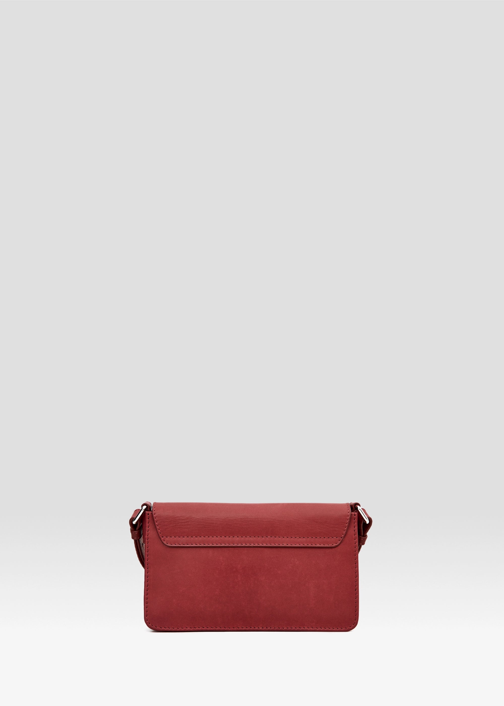 Back view of the Philini Mihaela Wallet Bag in red nappa leather, showing the softly tapered rectangular shape, stitched front flap, and adjustable leather strap with silver accents. 