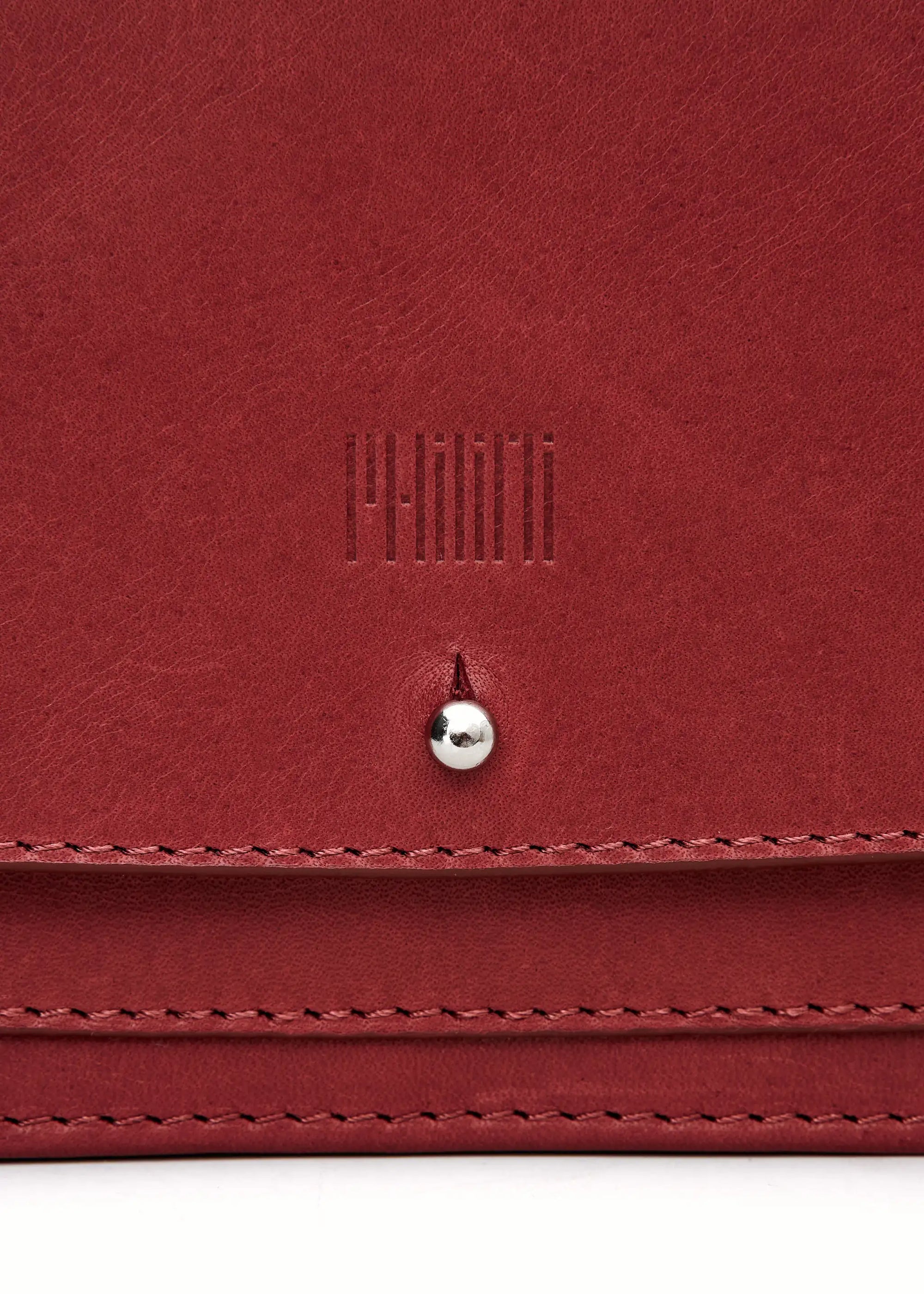  Close-up front view of the Philini Mihaela Wallet Bag in red Nappa leather, featuring a rectangular shape, front flap with silver cufflink closure, adjustable leather strap with silver accents, and a stamped logo. This minimalist wallet crossbody blends conscious luxury with timeless leather craftsmanship