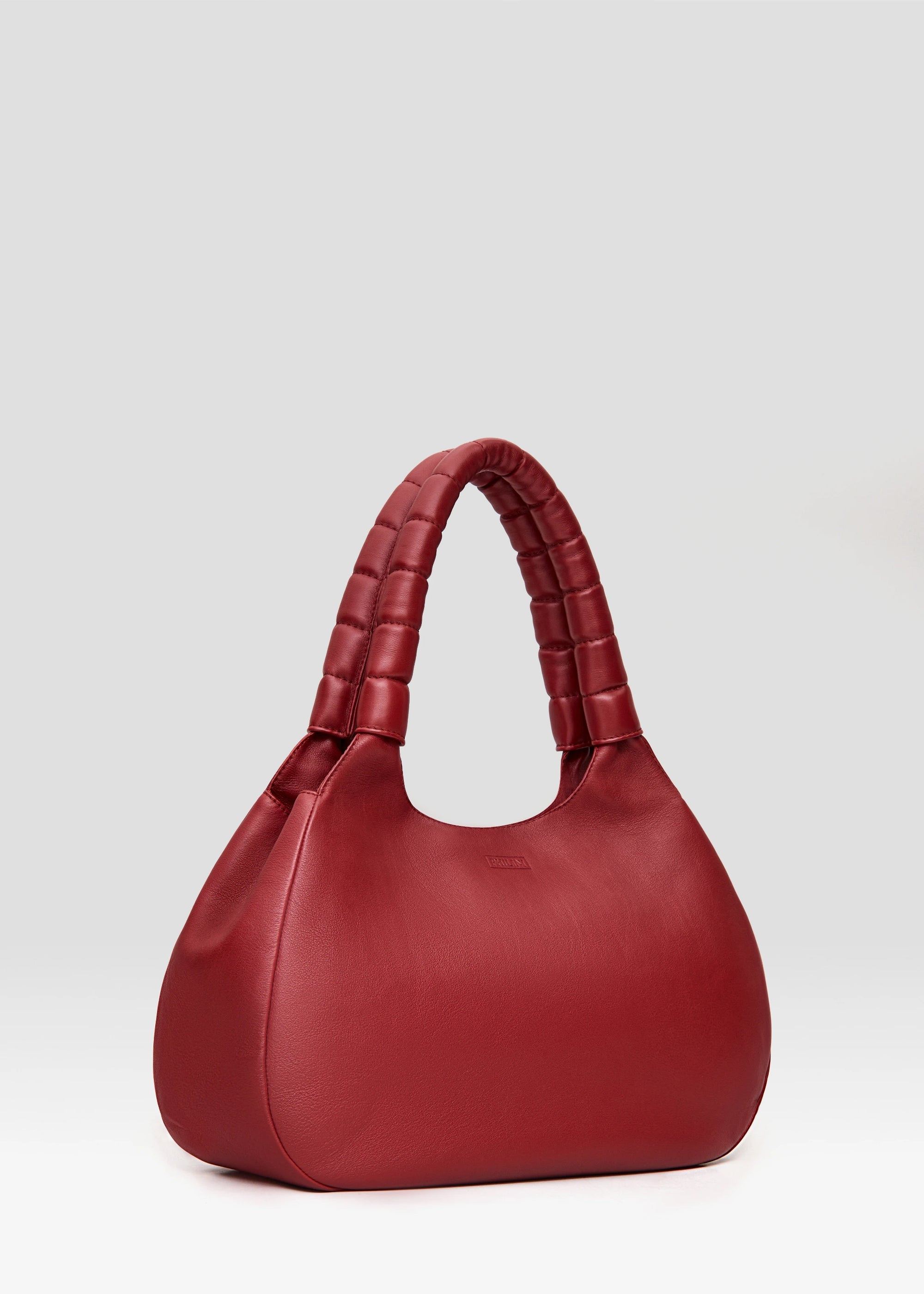 Angled view of the Philini Adreann Hobo Bag in red nappa leather, featuring two integrated soft handles and a stamped logo. Soft leather hobo tote, premium minimalist purse