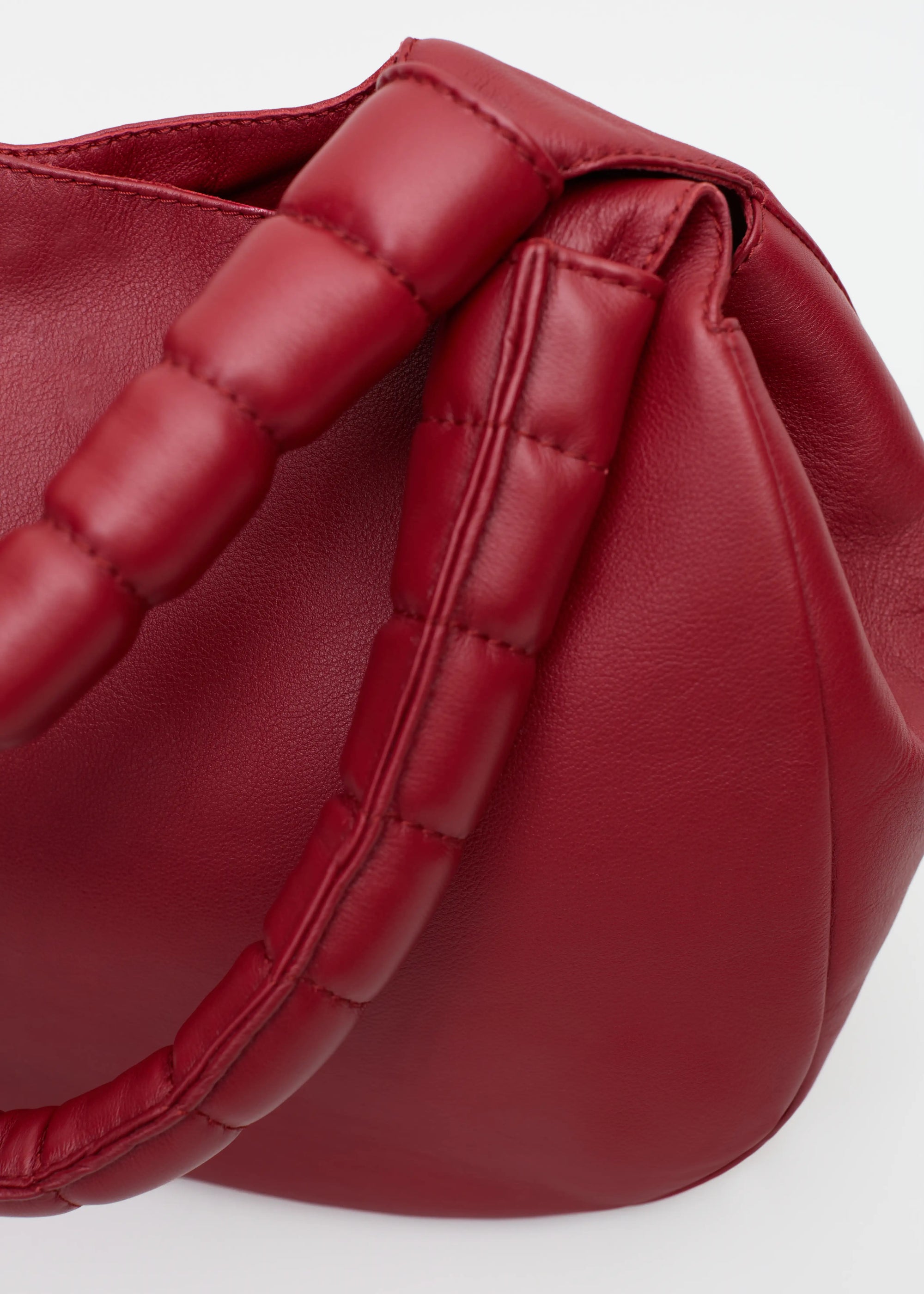 Close-up of the Philini Adreann Hobo Bag in red nappa leather, showing two integrated soft handles and a stamped logo. Individually crafted soft leather hobo handbag