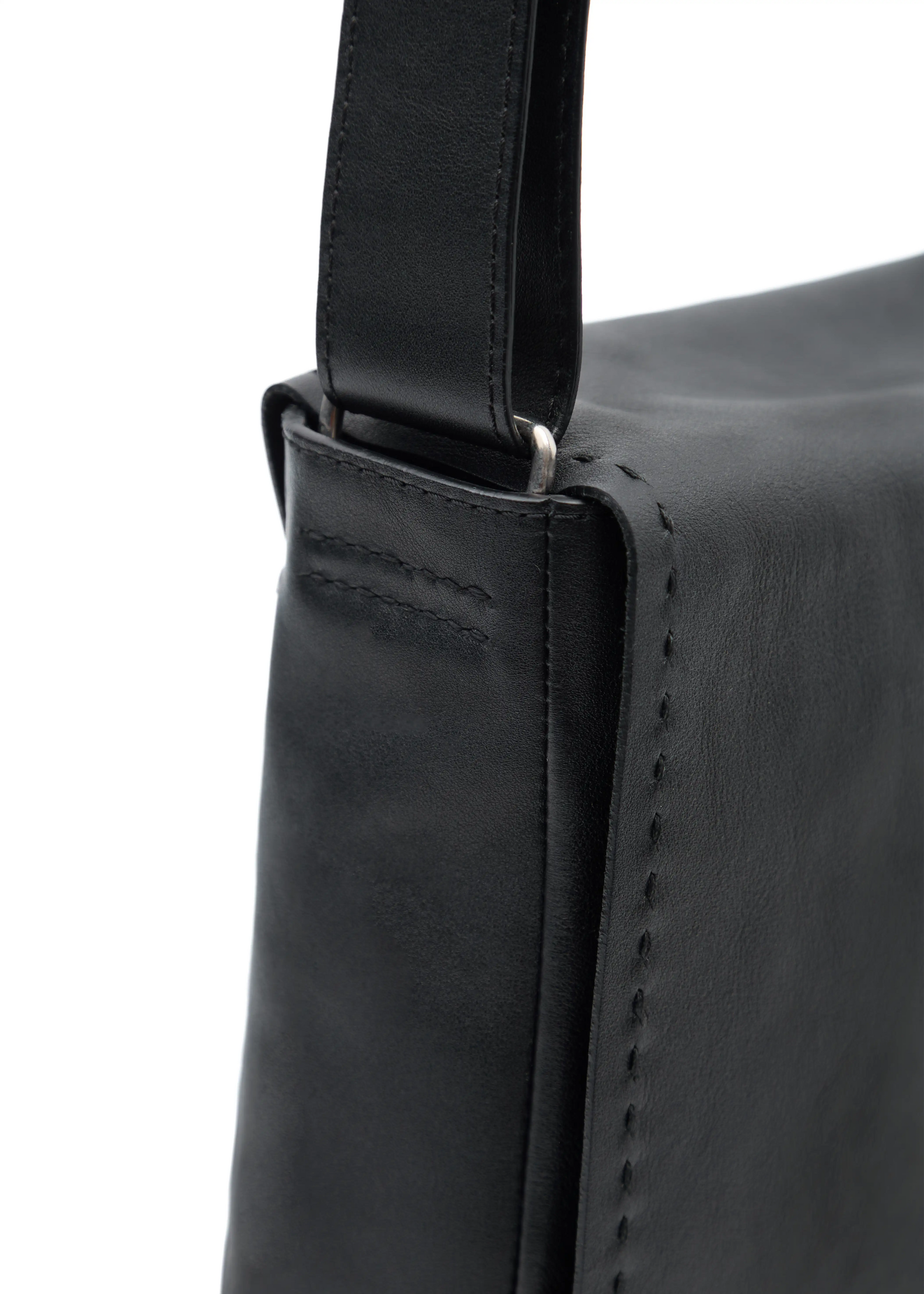 Close-up of Philini Anastasia Messenger Bag in black aniline nappa leather, showing black perimeter stitching, silver hardware on handle, and hand-stitched details. The handcrafted designer leather bag 