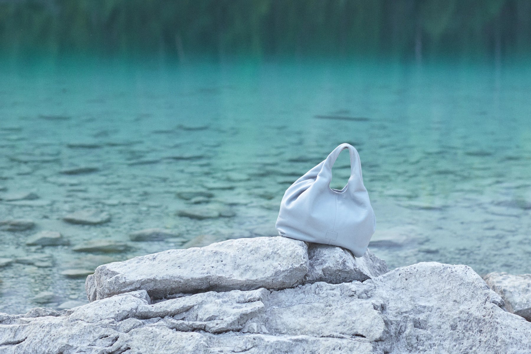 Light grey hobo bag on the lake side. The bag is soft and roomy. Has almost no hardware and is very elegant. 