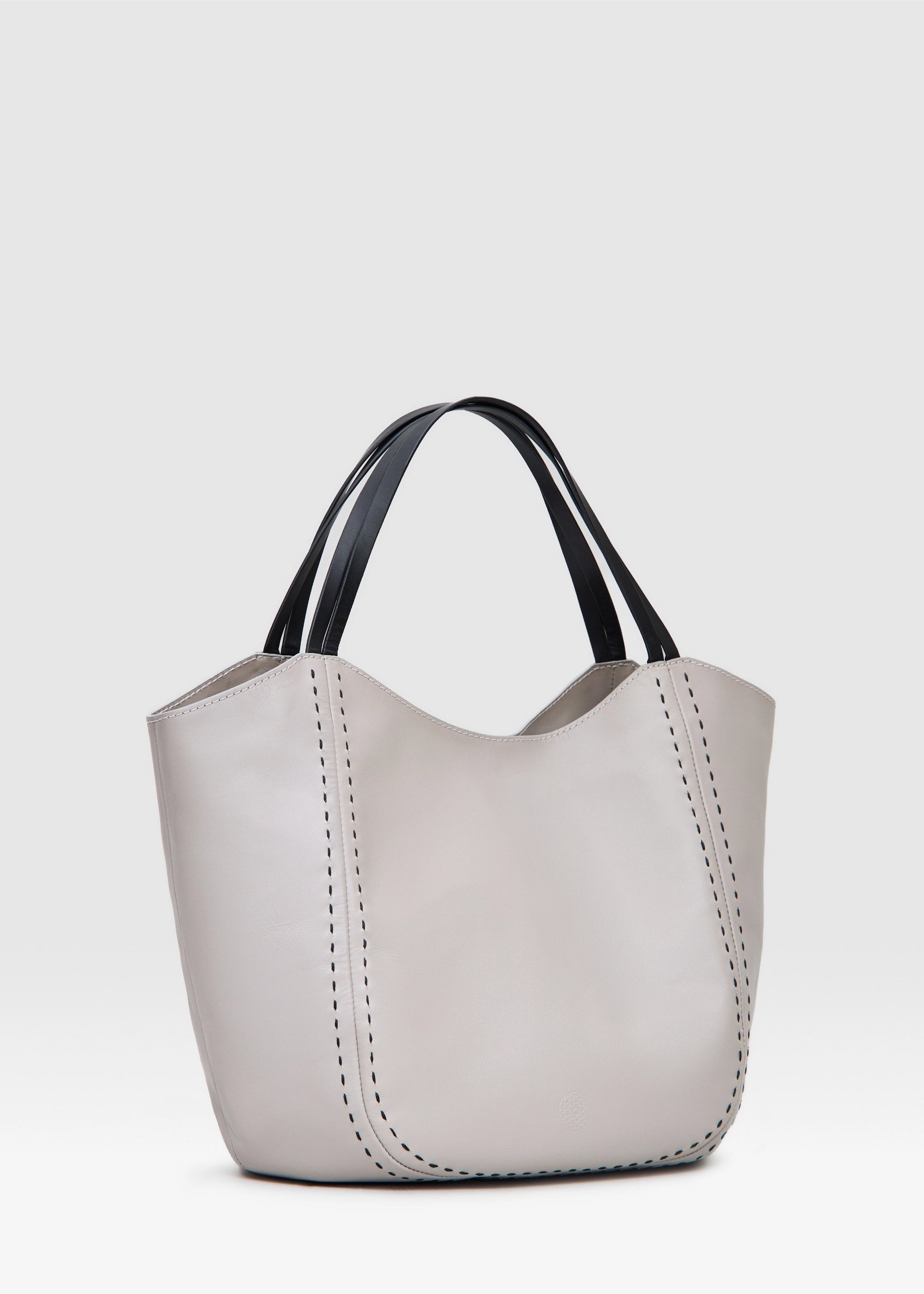 Side view of the Philini Charlotte Tote Bag in taupe aniline calf leather, featuring two double flat leather handles, magnetic button closure, and front accented by black hand-stitching. This elegant structured tote is a premium handcrafted leather handbag
