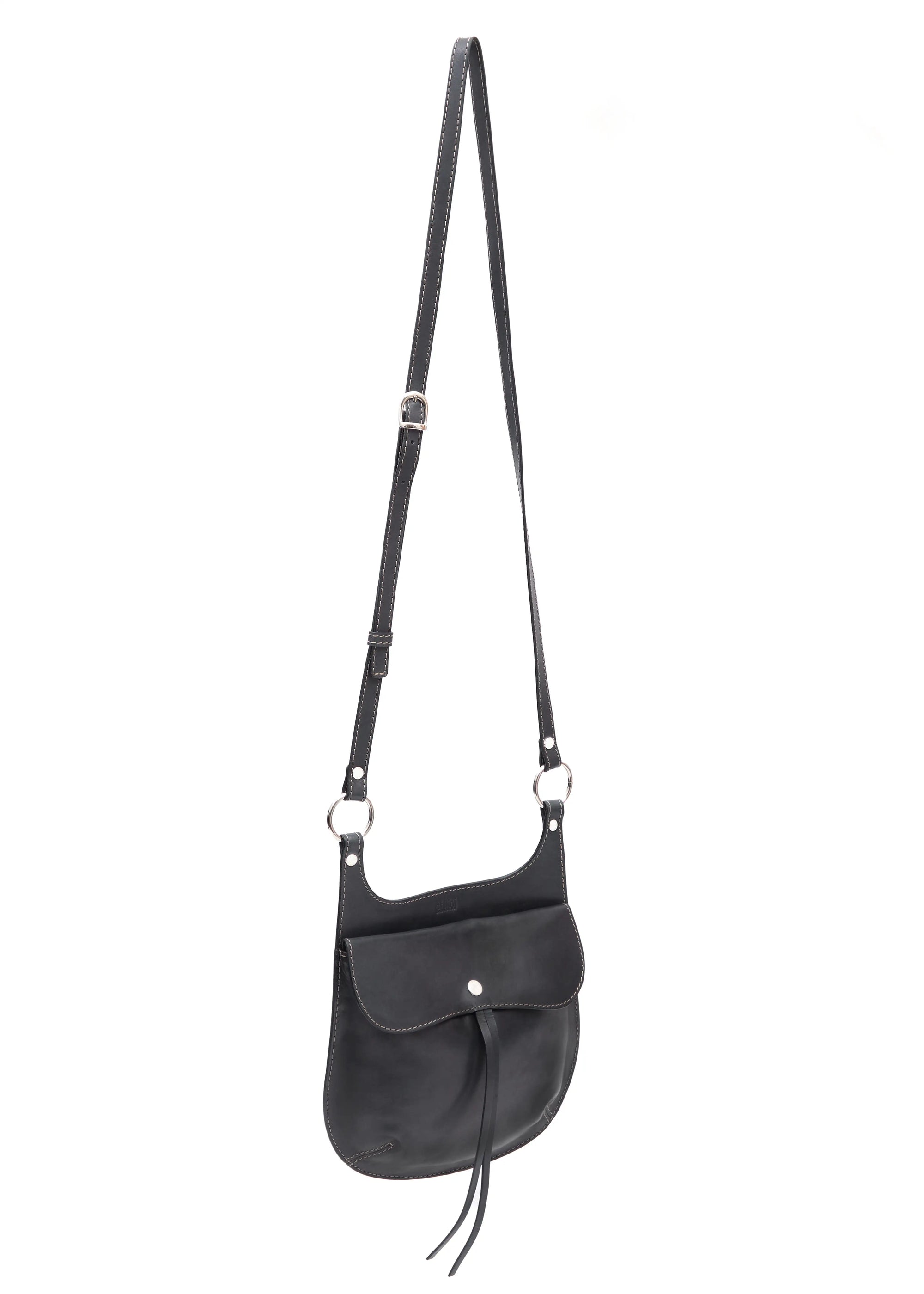 Side view of the Philini Cowboy Crossbody Bag in black calf leather, rounded saddle silhouette with front flap, snap closure, and long adjustable strap. Sustainable mini designer bag for women