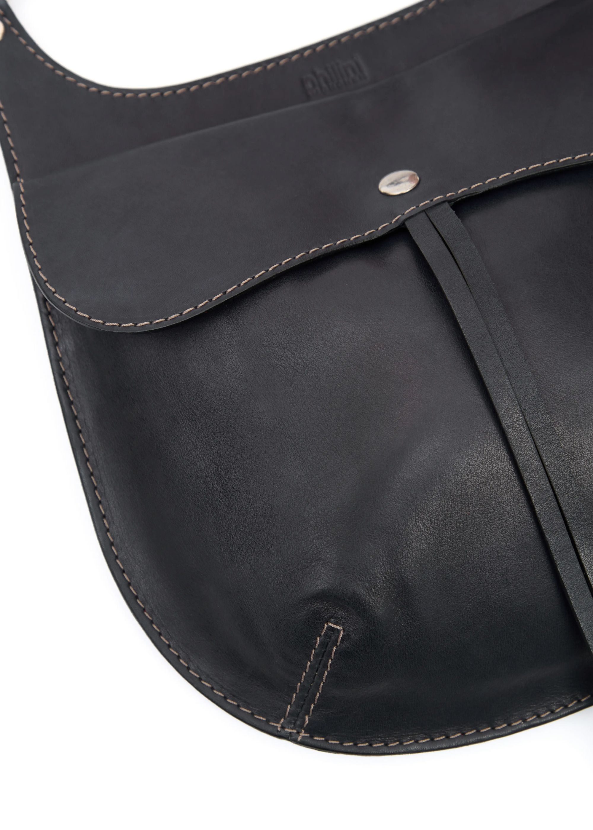 Close-up of the Philini Cowboy Crossbody Bag in black calf leather, rounded saddle silhouette with front flap, snap button closure, and stamped logo. Sustainable minimalistic designer purse