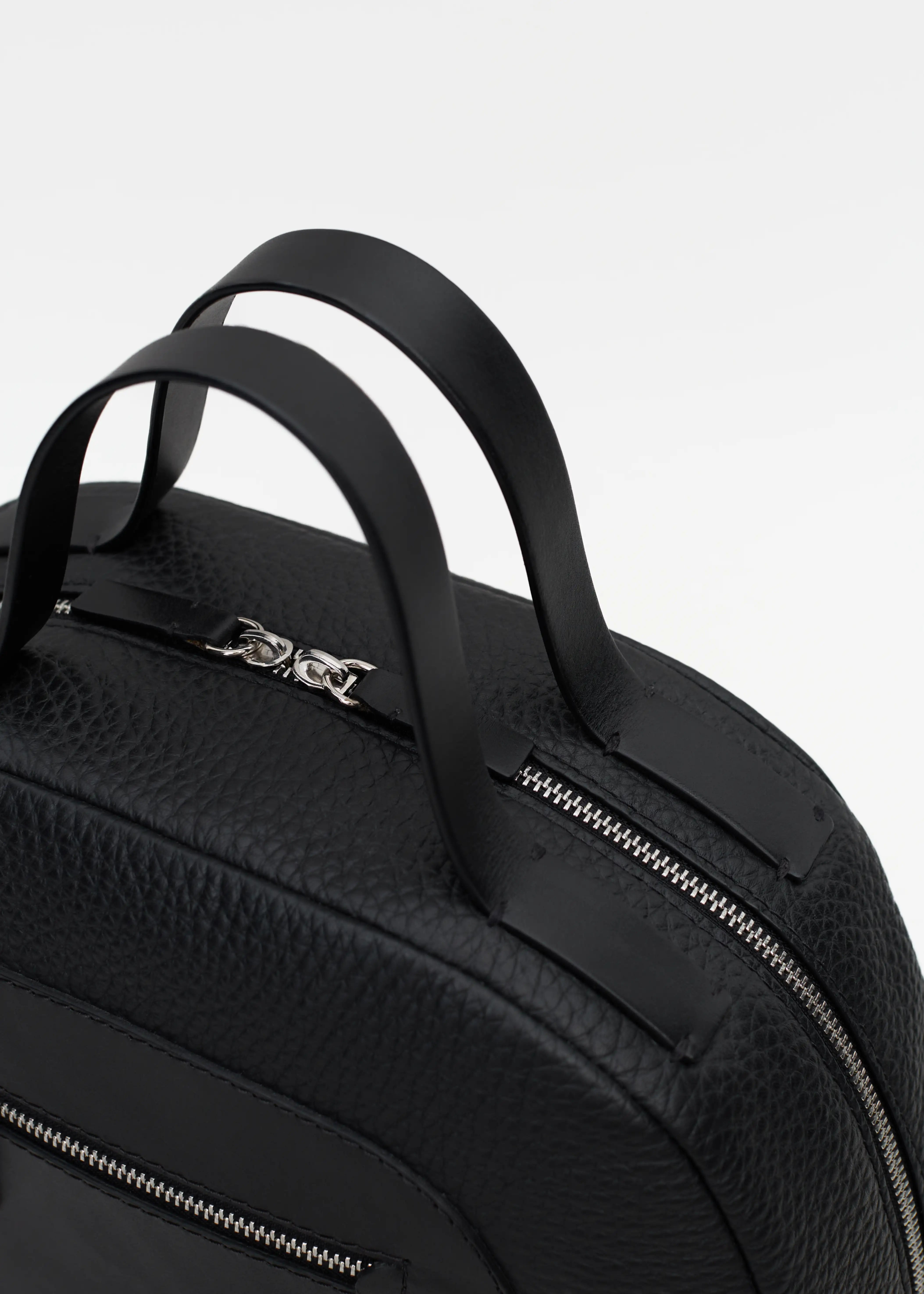 Top view of the Philini Domi Black Dome Handbag, crafted from black buffalo leather with hand-stitched full-grain leather short handles, visible silver rivets, and a sleek zipper. The sustainable, handcrafted luxury leather bag.