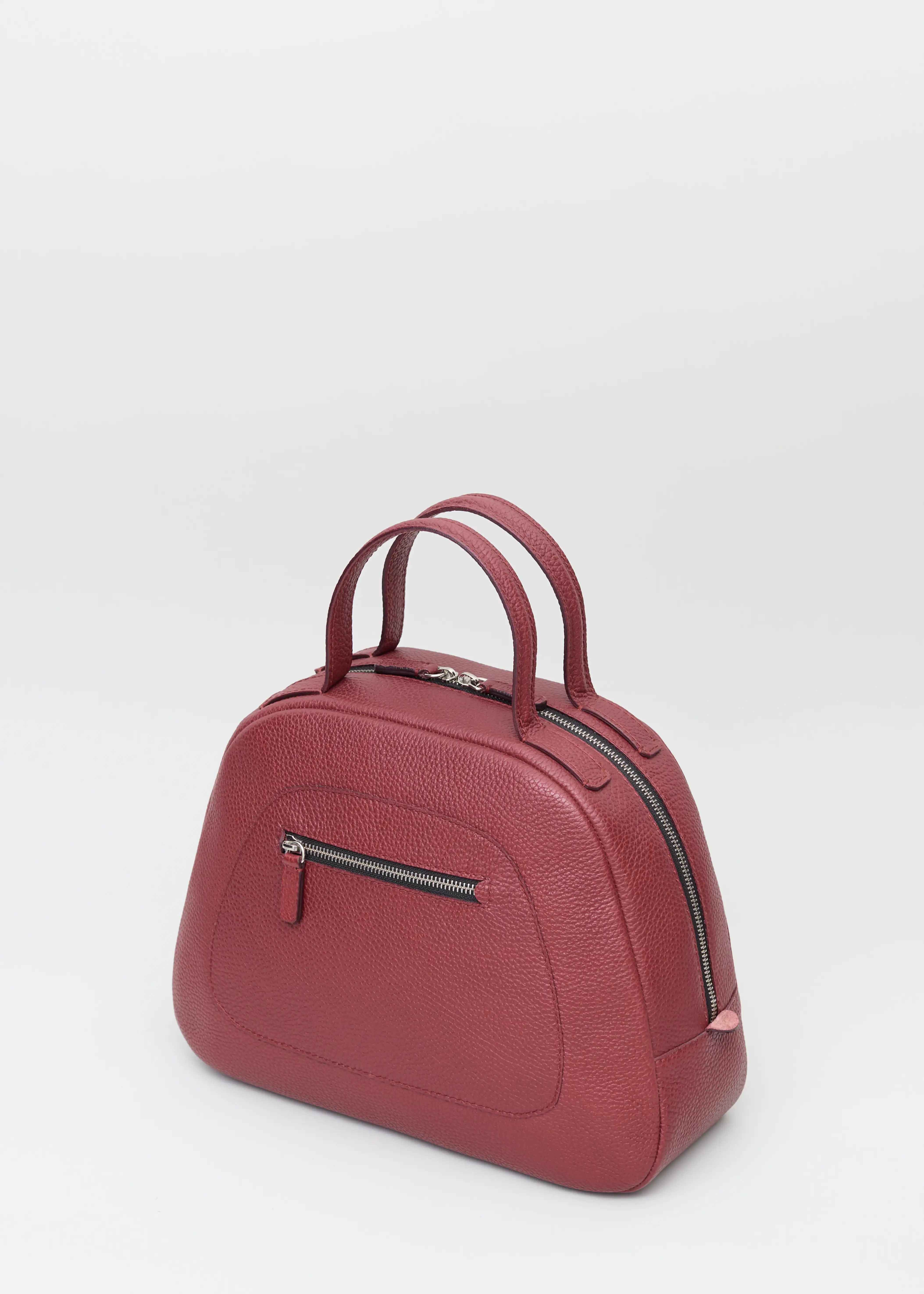 Side view of the Philini Domi Handbag in red calf leather, showcasing the dome shape, short handles, silver rivets, front zip pocket, and zipper closure. The elegant, premium accessory for timeless style. 