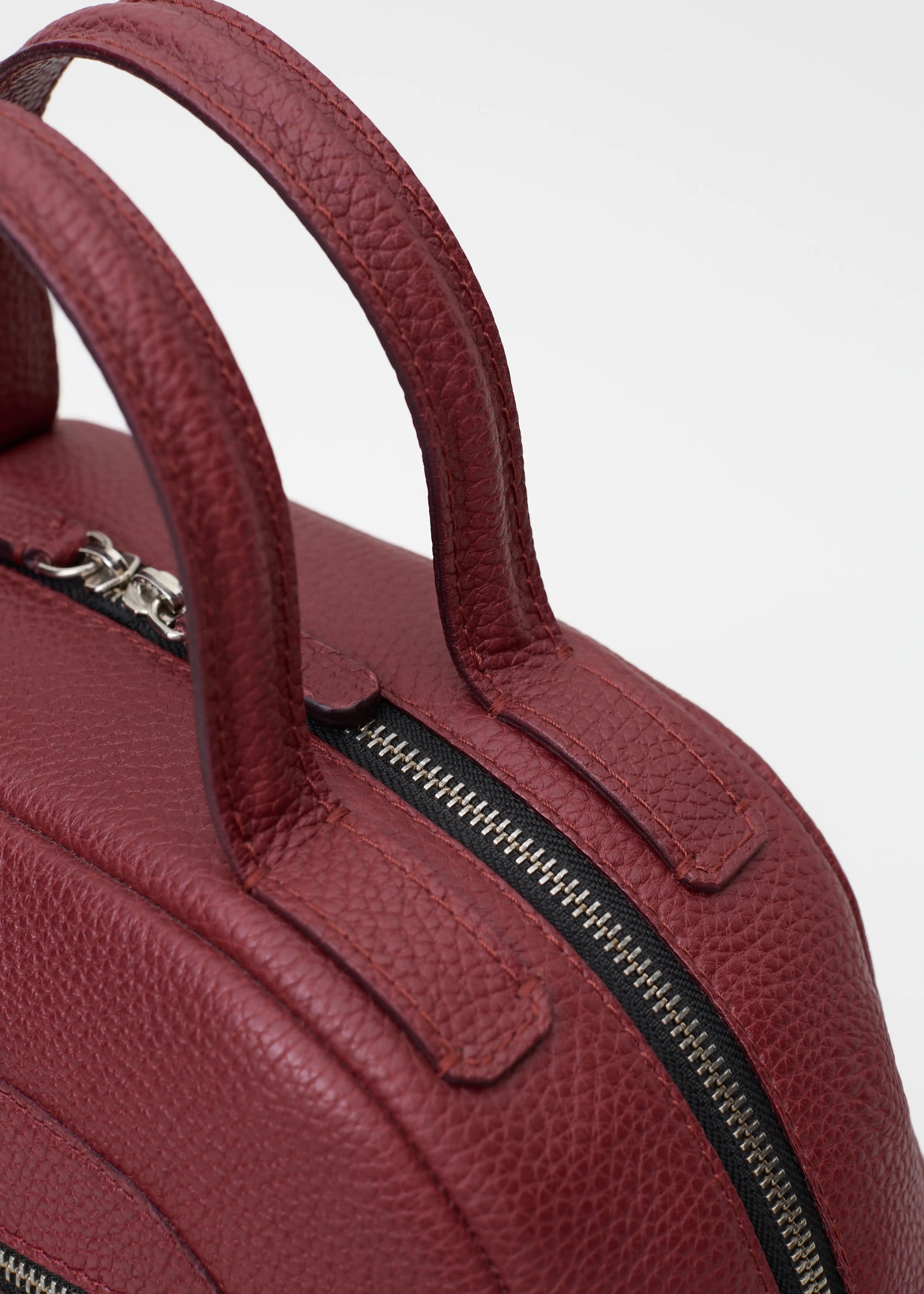 Top view of the Philini Domi Black Dome Handbag, crafted from premium calf leather with silver rivets, a sleek zipper, and short leather handles. Minimalist leather handbag designed for refined elegance and timeless style