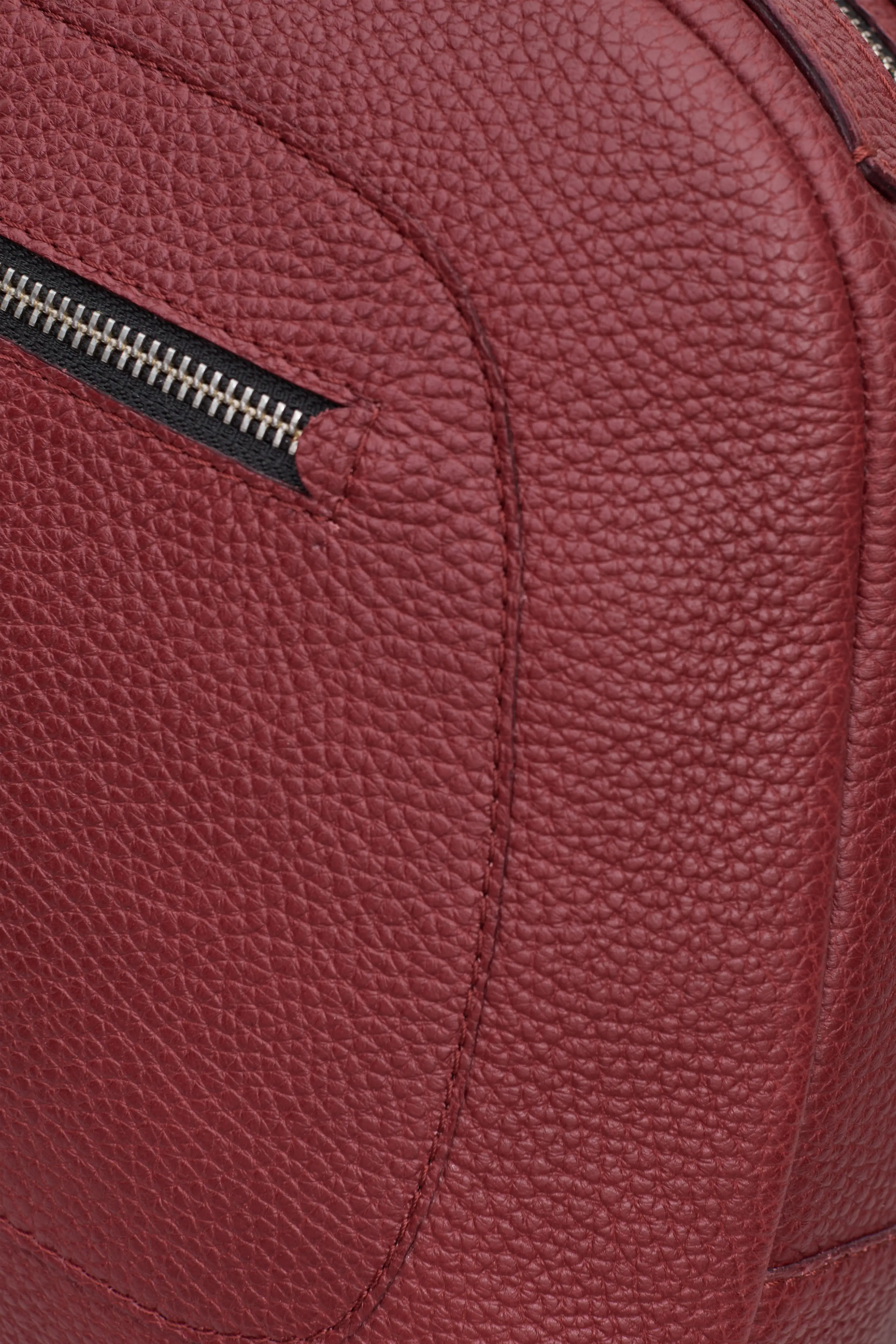 Detailed view of the Philini Domi red Handbag in dome shape, handcrafted from calf leather and finished with short leather handles, silver rivets, and a zipper closure. The interior features a vanilla-colored lining and zippered inner pockets.