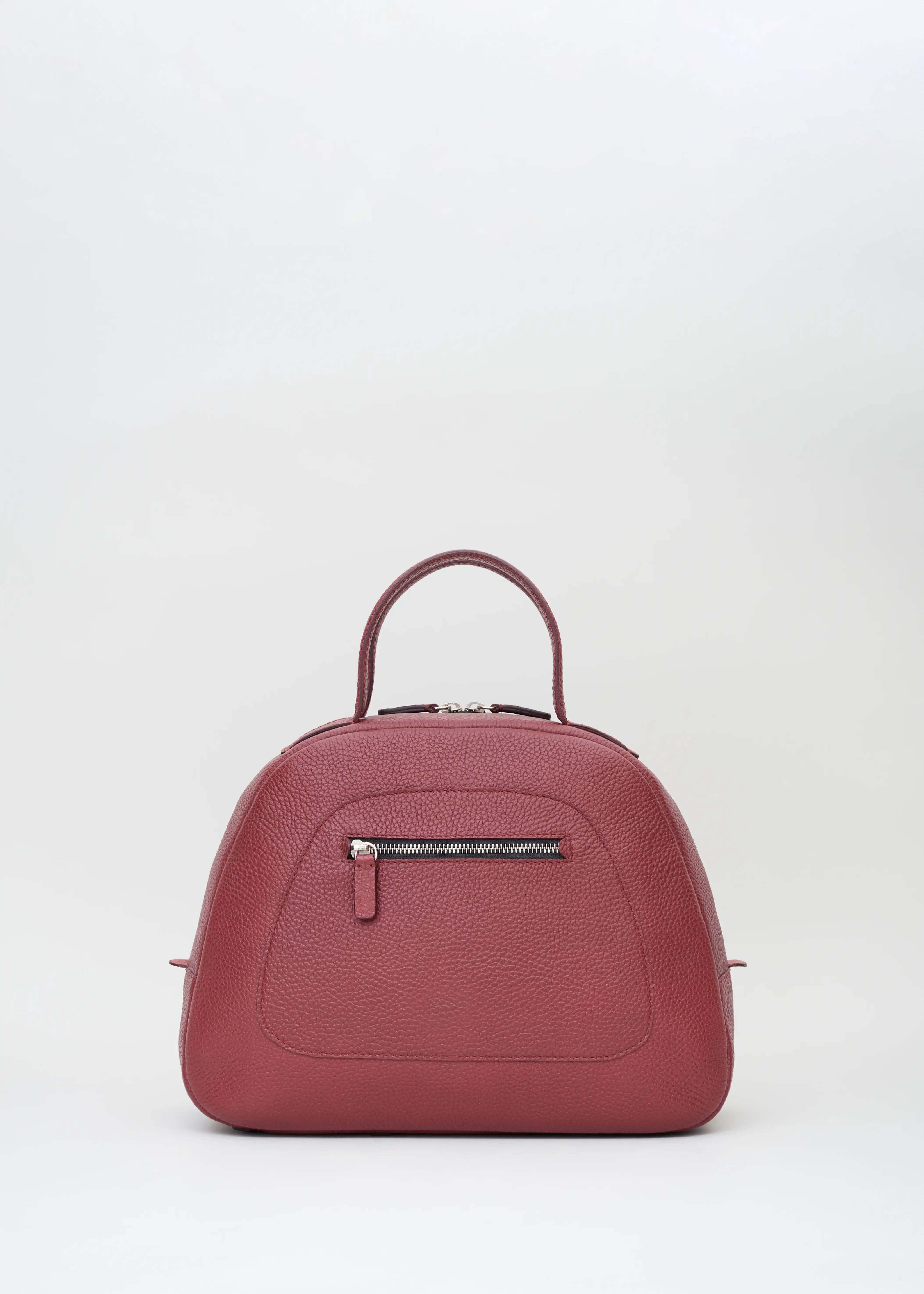 Front view of the Philini Domi Handbag in red calf leather, featuring a dome shape, short handles, silver rivets, front zip pocket, and a sleek silver zipper. This handcrafted designer leather bag blends minimalist design with elegant.