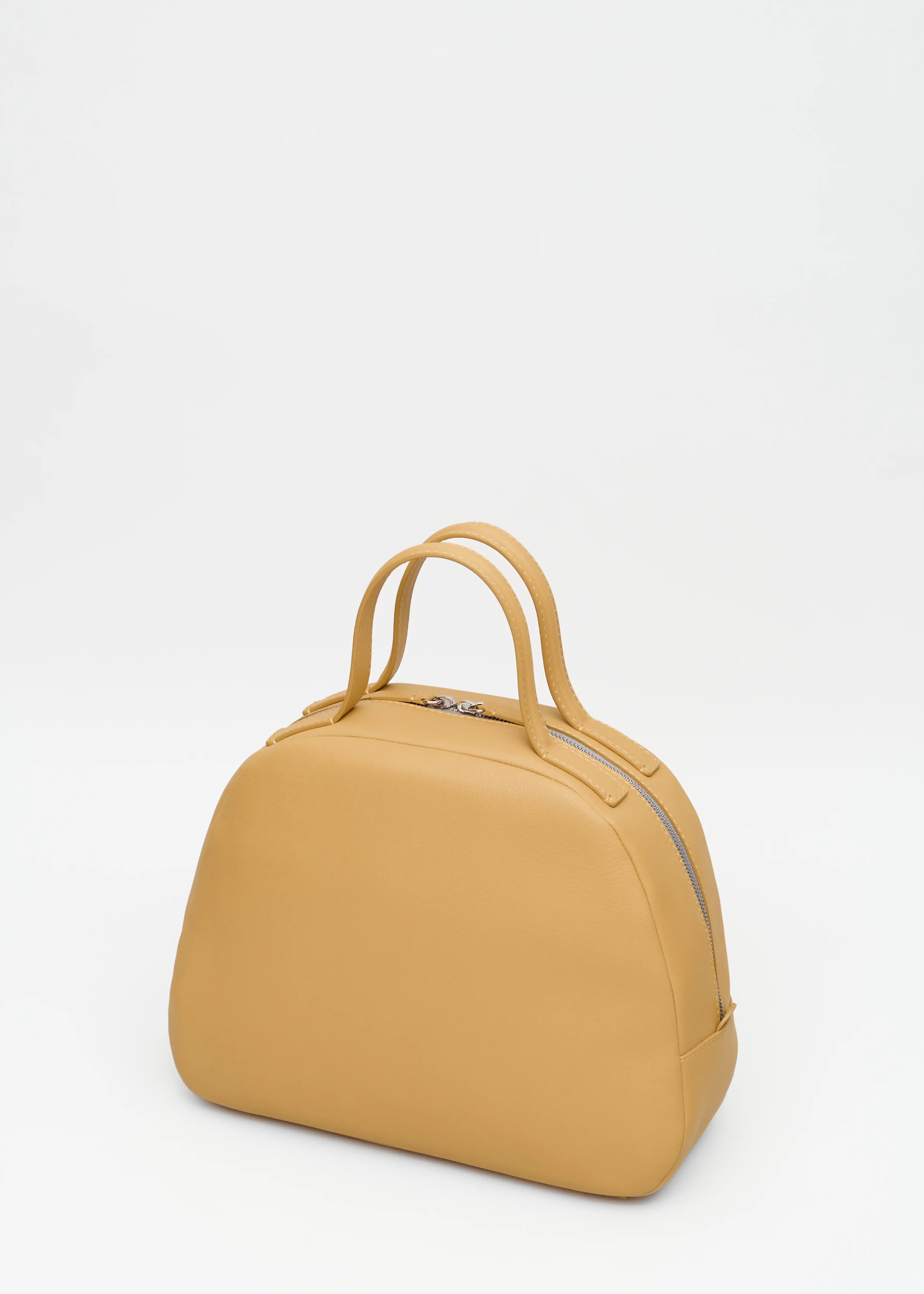 Back view of the Philini Domi Handbag in yellow nappa leather, featuring a dome shape, short handles, silver rivets, and zipper. Handmade leather bag with minimalist design