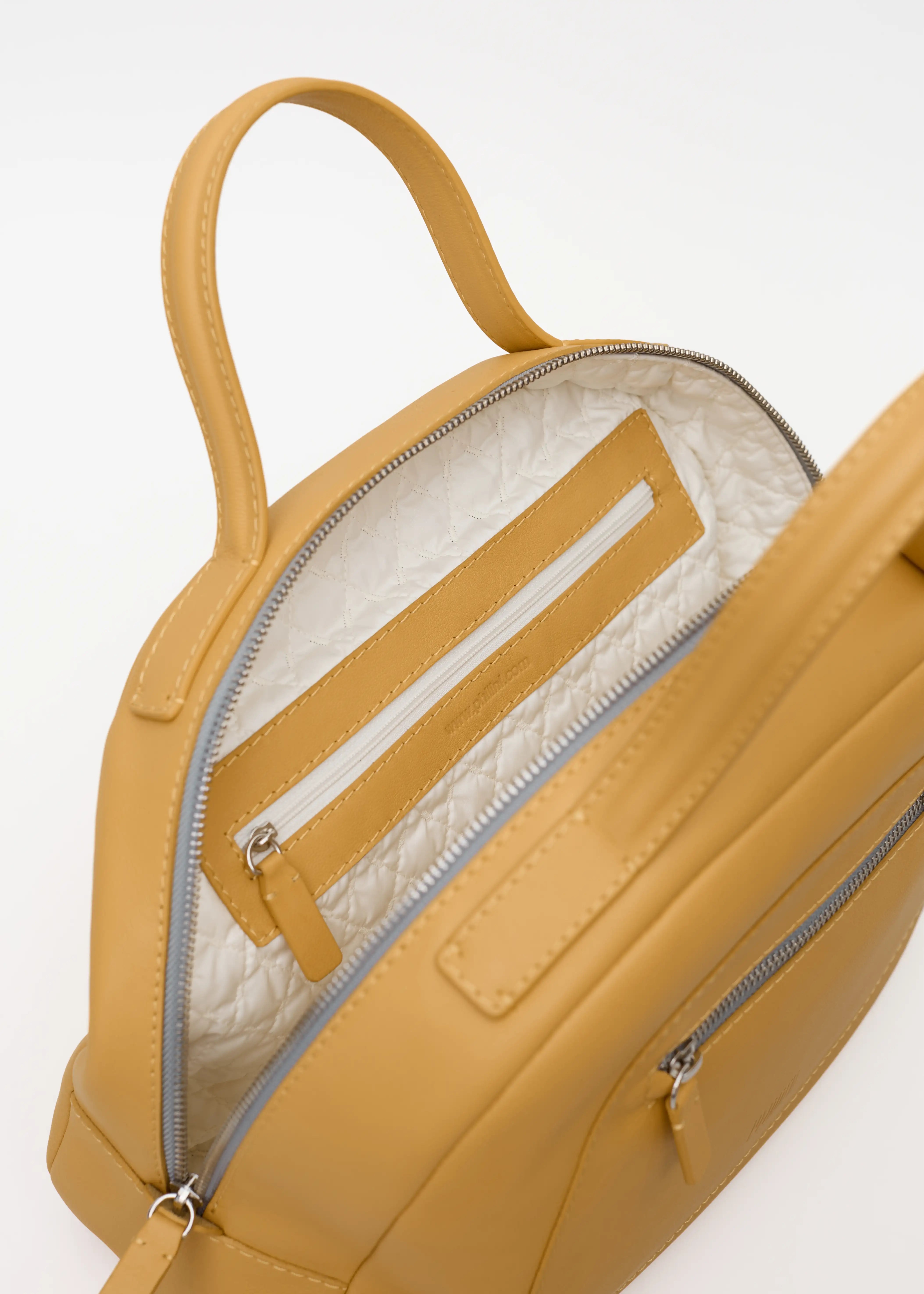 Inside view of the Philini Domi Handbag in yellow nappa leather, showing vanilla-patterned lining, two zip compartments, stamped plate, and hand-stitched details. Handcrafted luxury bag with elegant design and lasting style. 