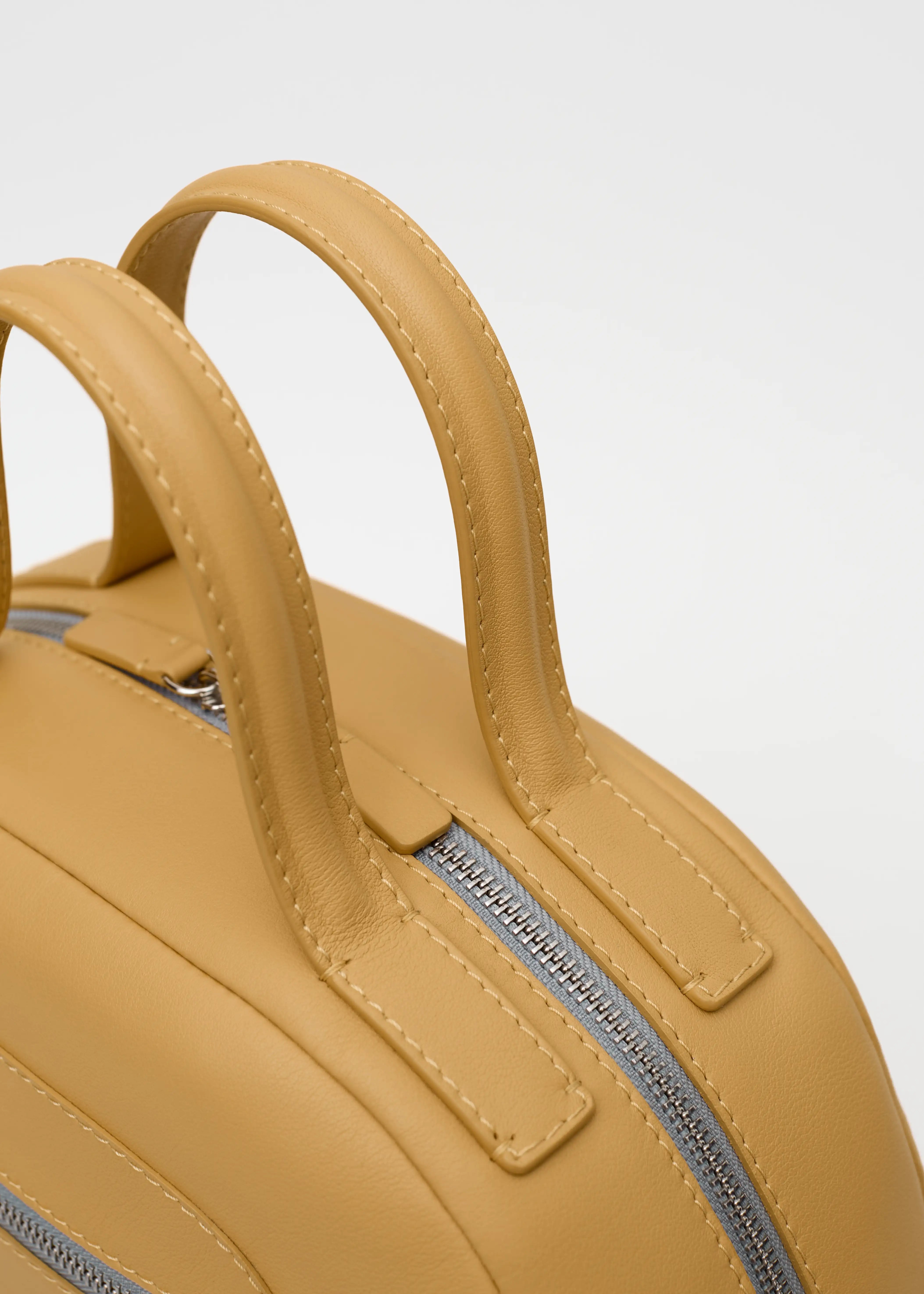 Top view of the Philini Domi Yellow Dome Handbag in premium nappa leather, featuring silver rivets, zipper, and short leather handles. Minimalist leather bag for elegant everyday use.