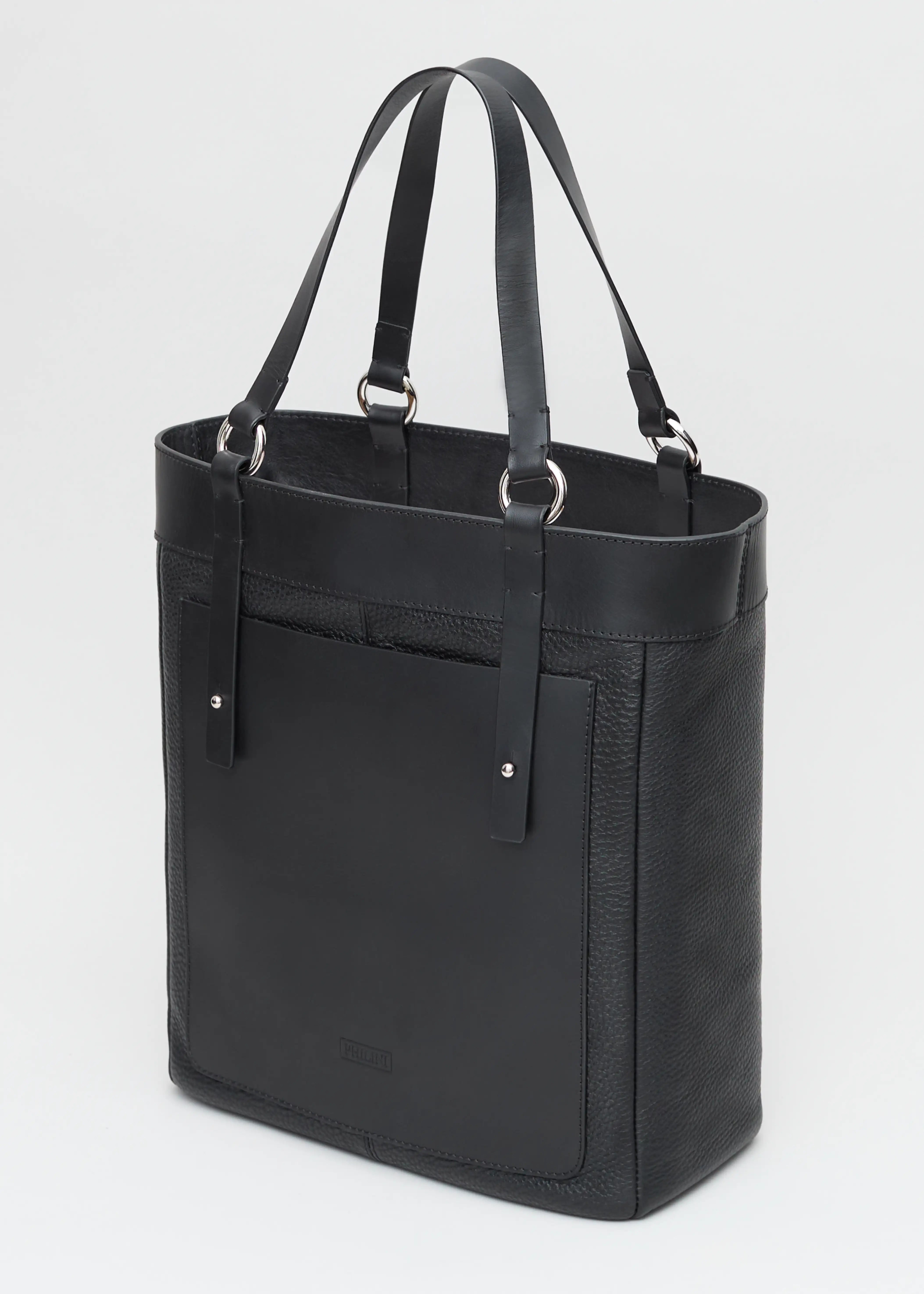 Side view of Philini Elena Black Tote Bag in two types of genuine leather, a full-grain leather exterior pocket and silver details on the sturdy handles. This timeless and eco-friendly bag is perfect for modern women seeking elegance and functionality.