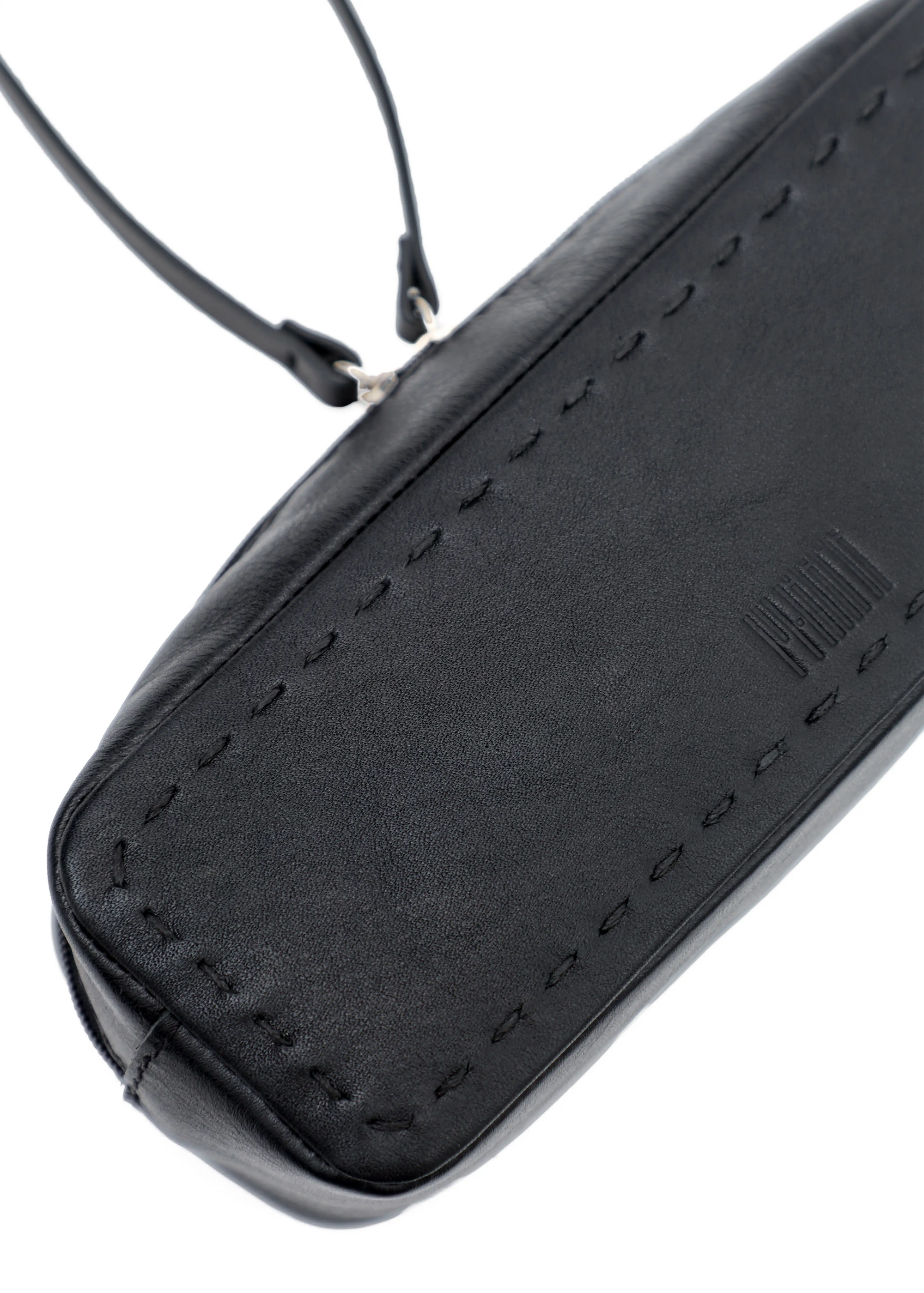 Close-up of the Philini Ellie Cosmetic Bag in black aniline leather, compact rectangular design with zip closure, leather pull, hand-stitched details, and stamped logo. Minimalist and leather makeup bag.