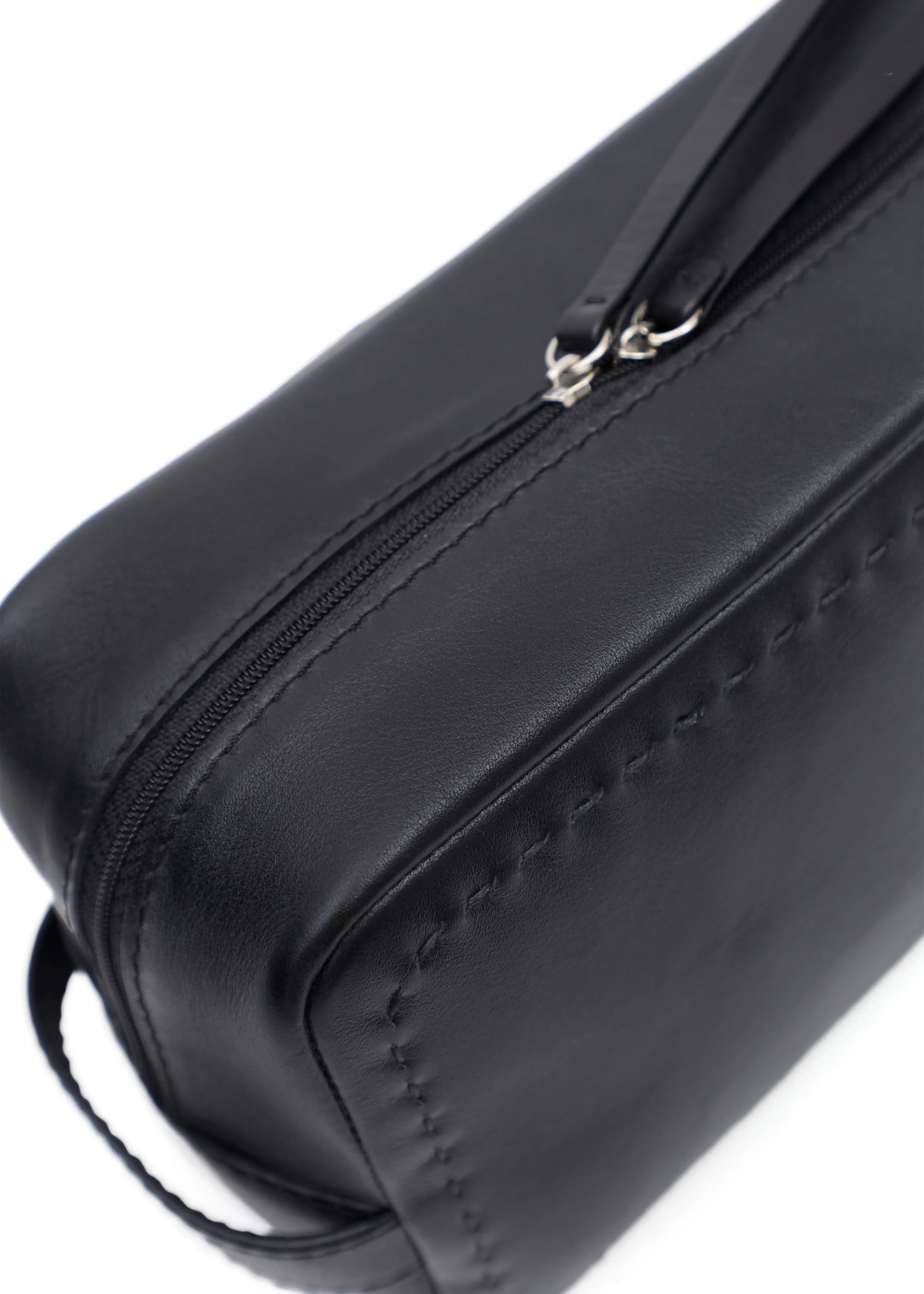 Close side view of the Philini Magdalena Pouch in black leather, featuring short handle, zip closure with leather pull, and fine hand-stitched edge. Compact black leather pouch.
