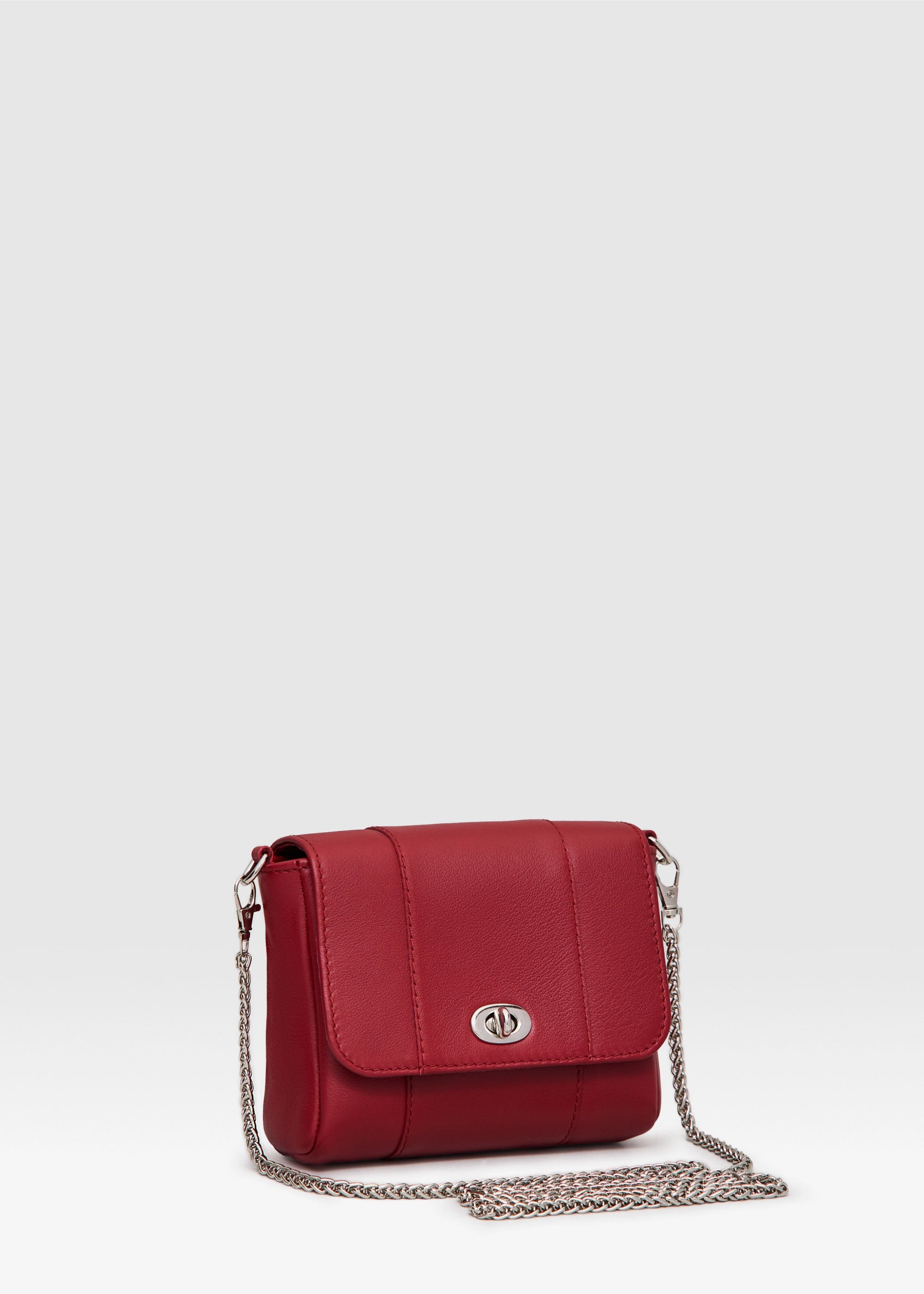 Side view of the Philini Marina Mini Crossbody Bag in red nappa leather, rectangular silhouette with front flap, silver clasp, and shoulder chain. Compact designer purse for women in bold red