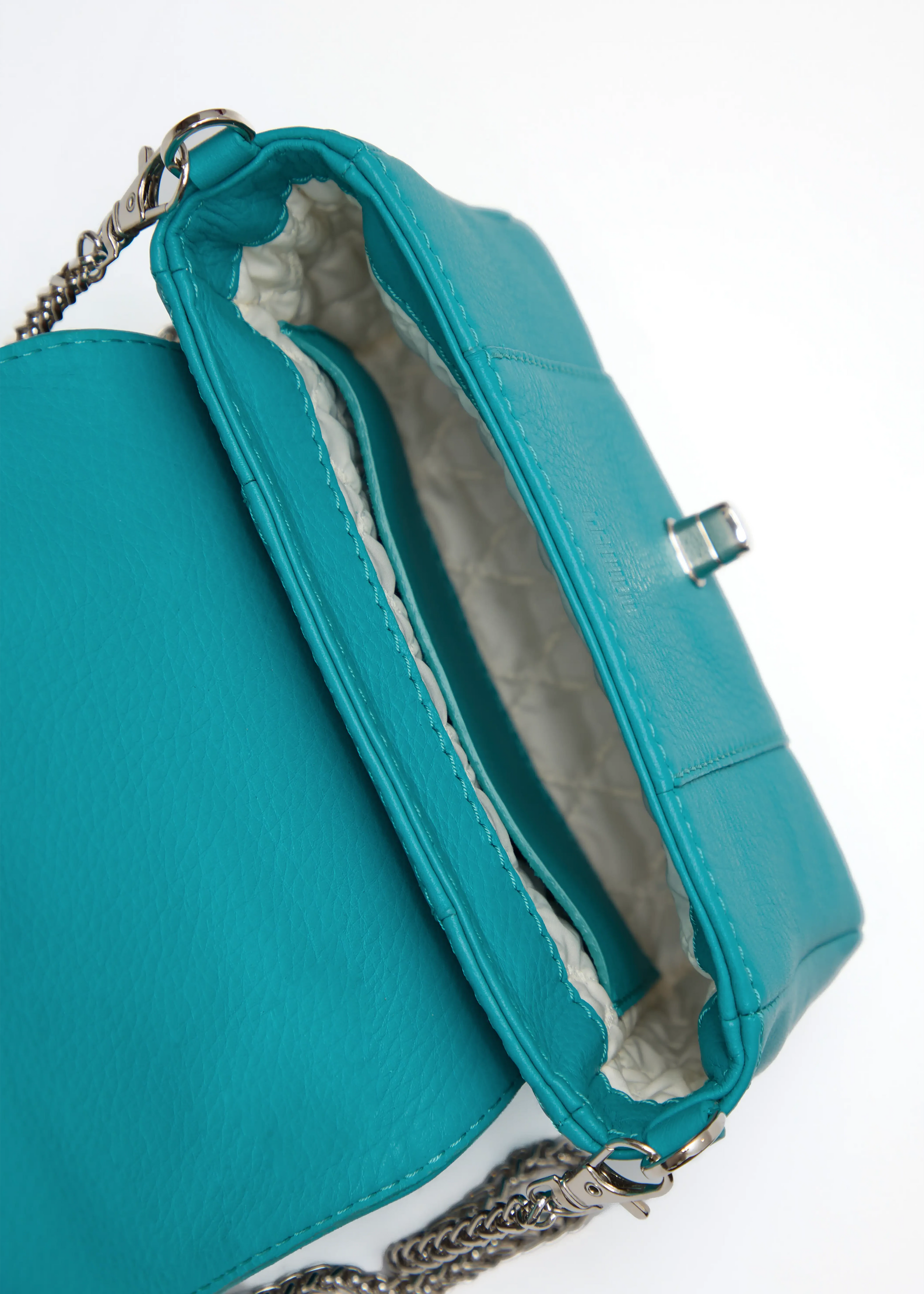 Inside view of the Philini Marina Mini Crossbody Bag in turquoise calf leather, showing open flap with silver clasp, chain with carabiner attachments, stitched vanilla lining, open compartment, and stamped logo. Bold and practical mini leather bag for everyday flair.
