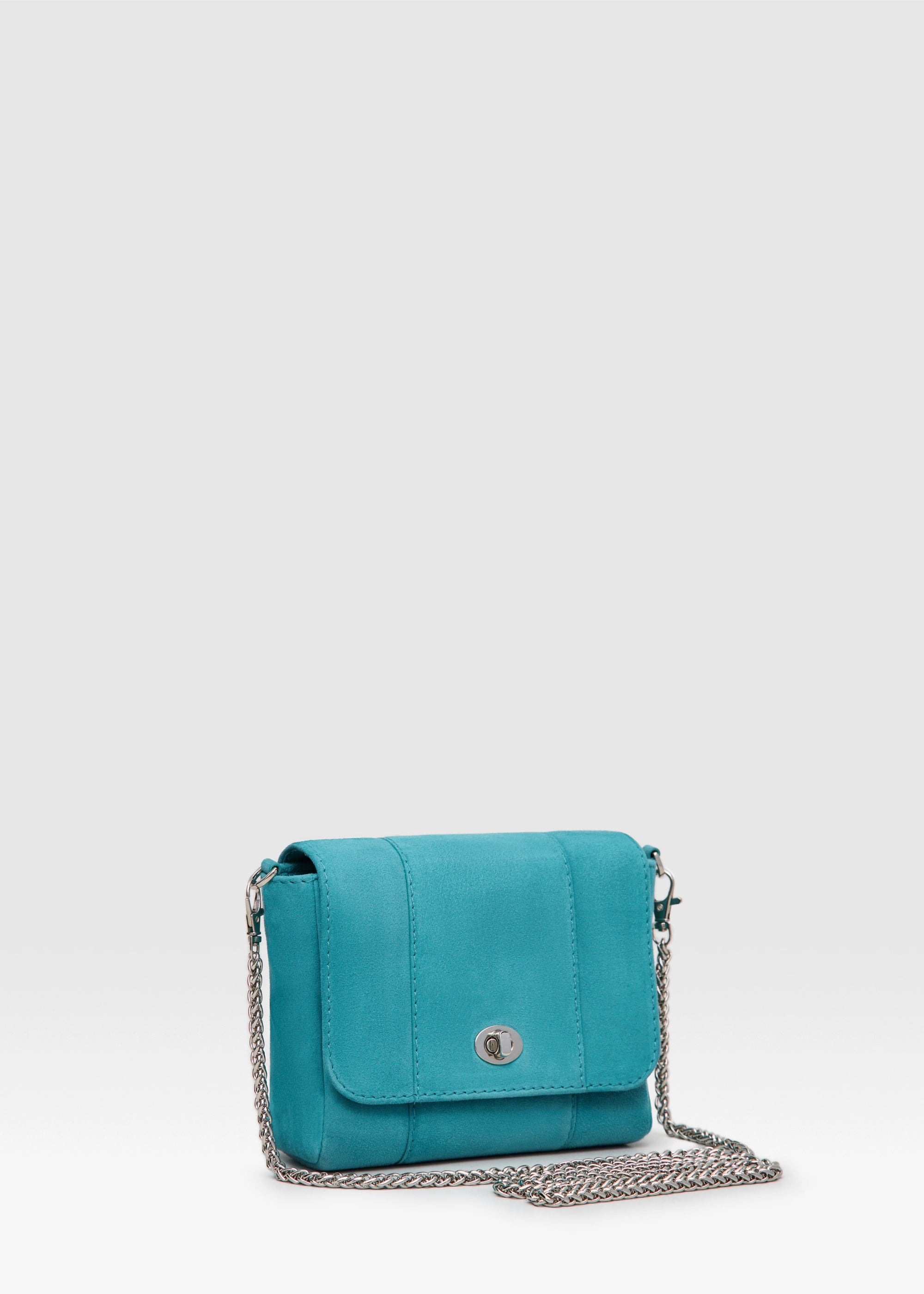 Side view of the Philini Marina Mini Crossbody Bag in turquoise suede leather, rectangular silhouette with front flap, silver clasp, and shoulder chain. Compact suede crossbody bag