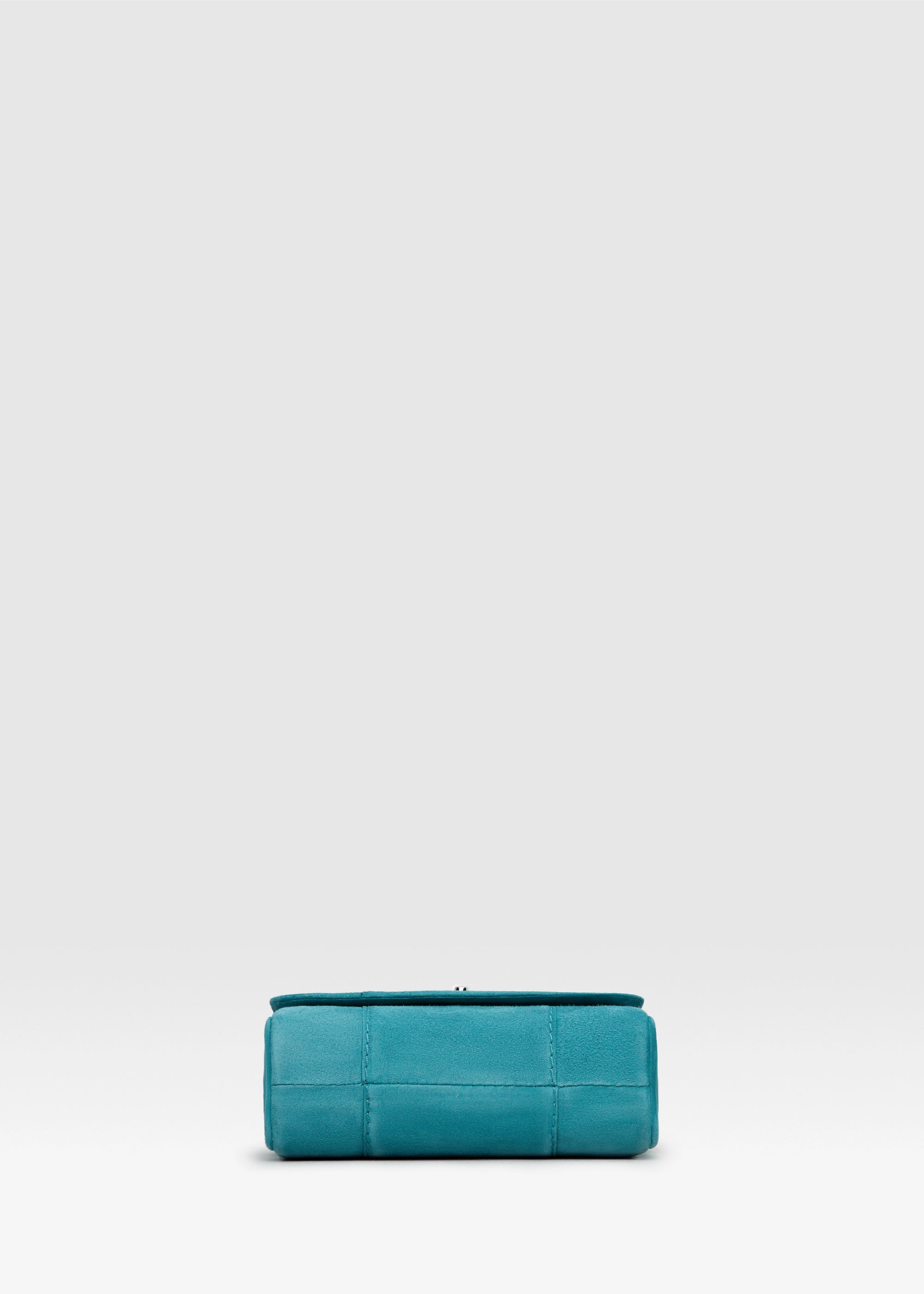 Bottom view of the Philini Marina Mini Crossbody Bag in turquoise suede leather, rectangular shape with front flap, silver clasp, and silver chain shoulder strap. Chic mini suede bag with a soft finish