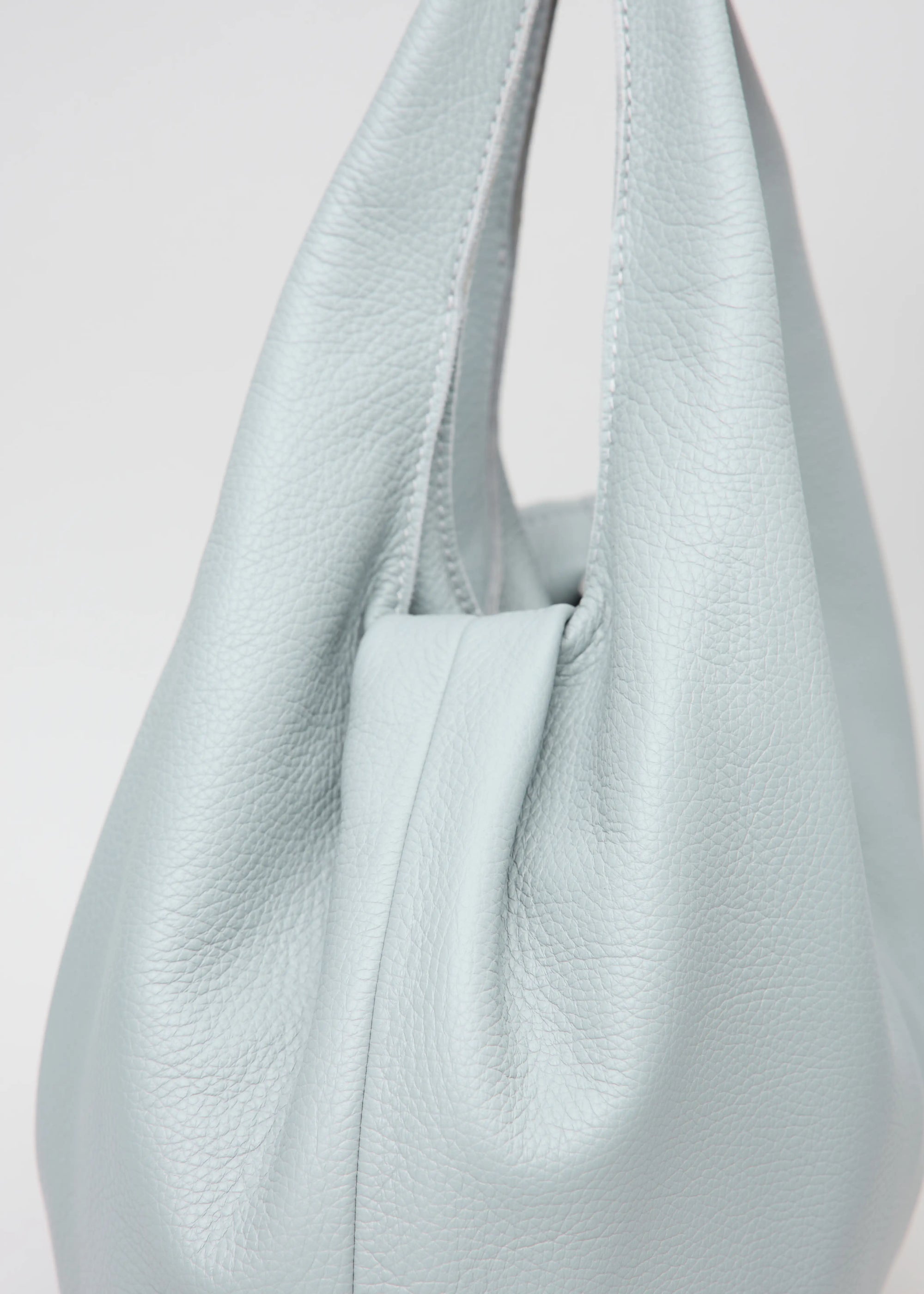 Detailed view of Philini Melanie Hobo Bag in grey buffalo leather, featuring two top handles and a stamped logo. Luxury minimalist shoulder bag for women