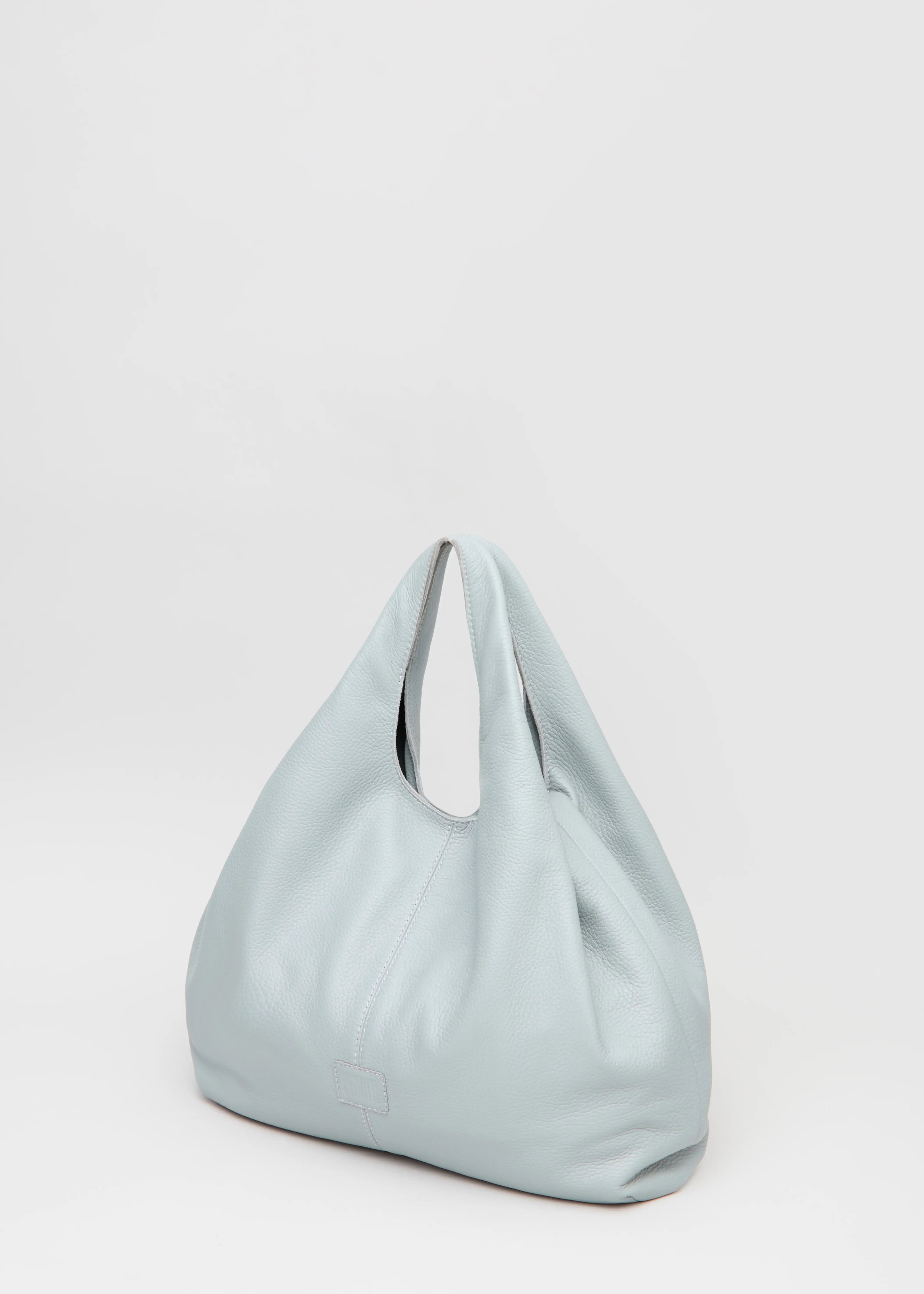 Side view of the Philini Melanie Hobo Bag in grey buffalo leather, showing two top handles, soft textured sides, and a stamped logo. High-quality slouchy leather handbag