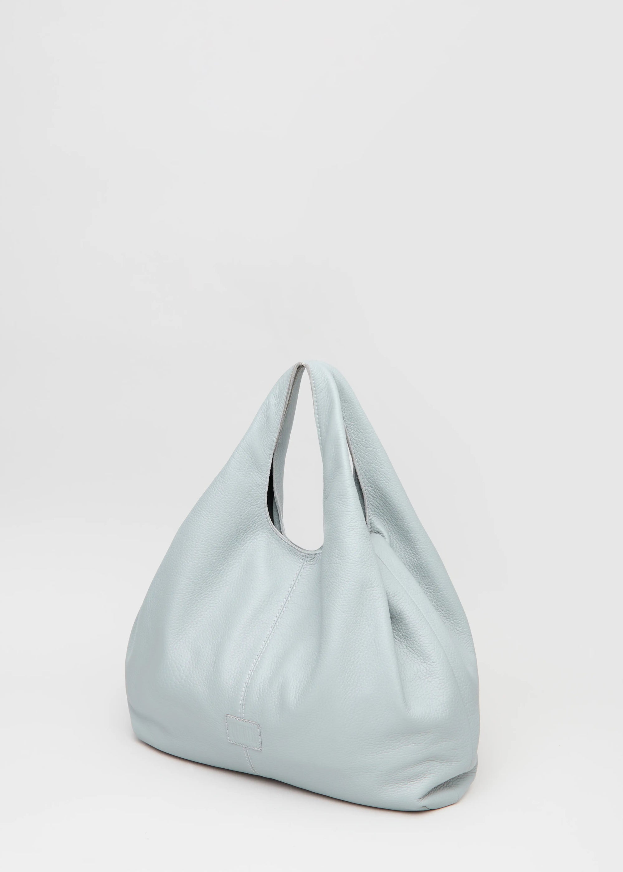 Side view of the Philini Melanie Hobo Bag in grey buffalo leather, showing two top handles, soft textured sides, and a stamped logo. High-quality slouchy leather handbag