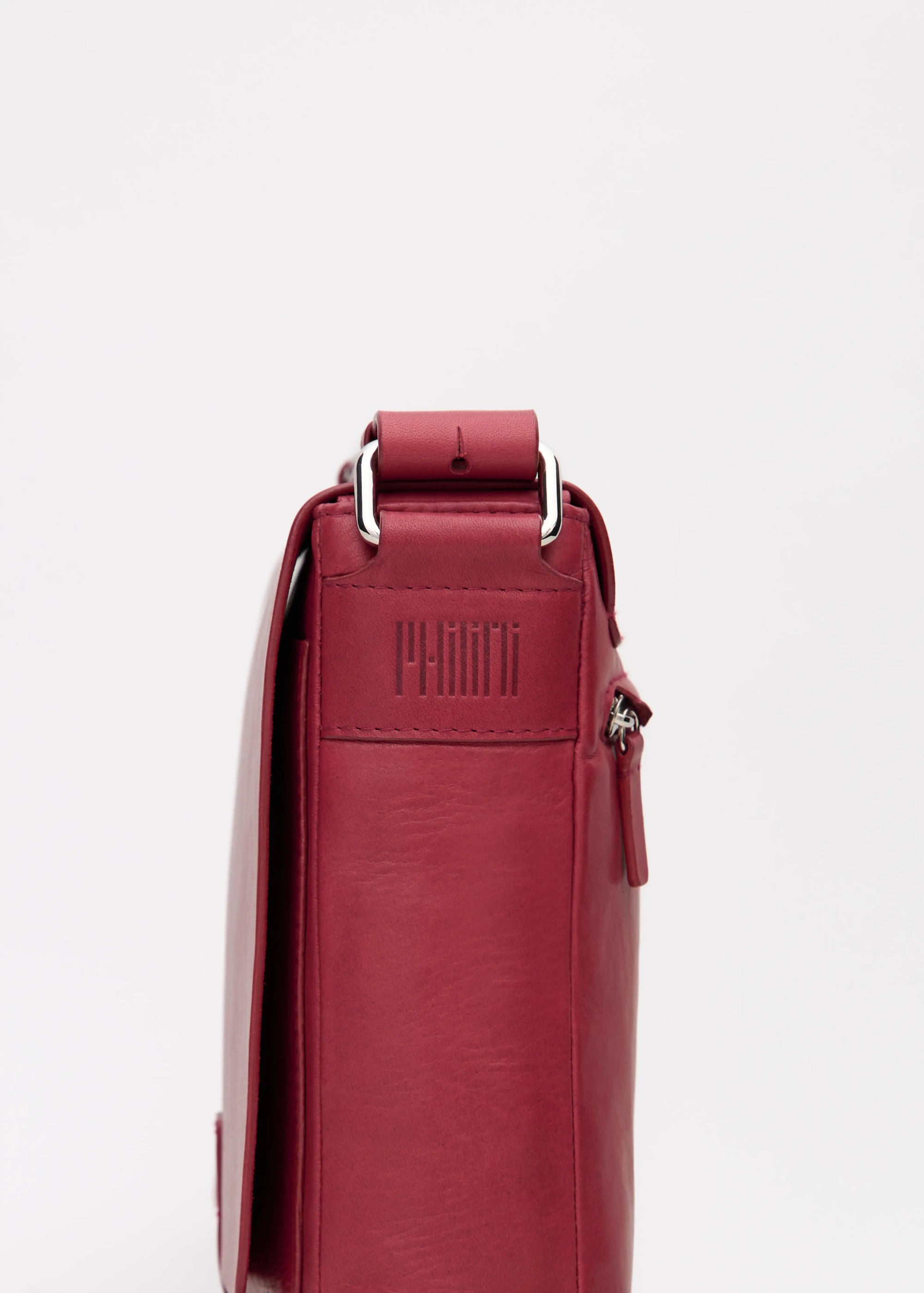 Side close-up of the Philini Olga shoulder bag in red aniline nappa leather, showing the stamped logo, silver hardware attaching the leather strap.
