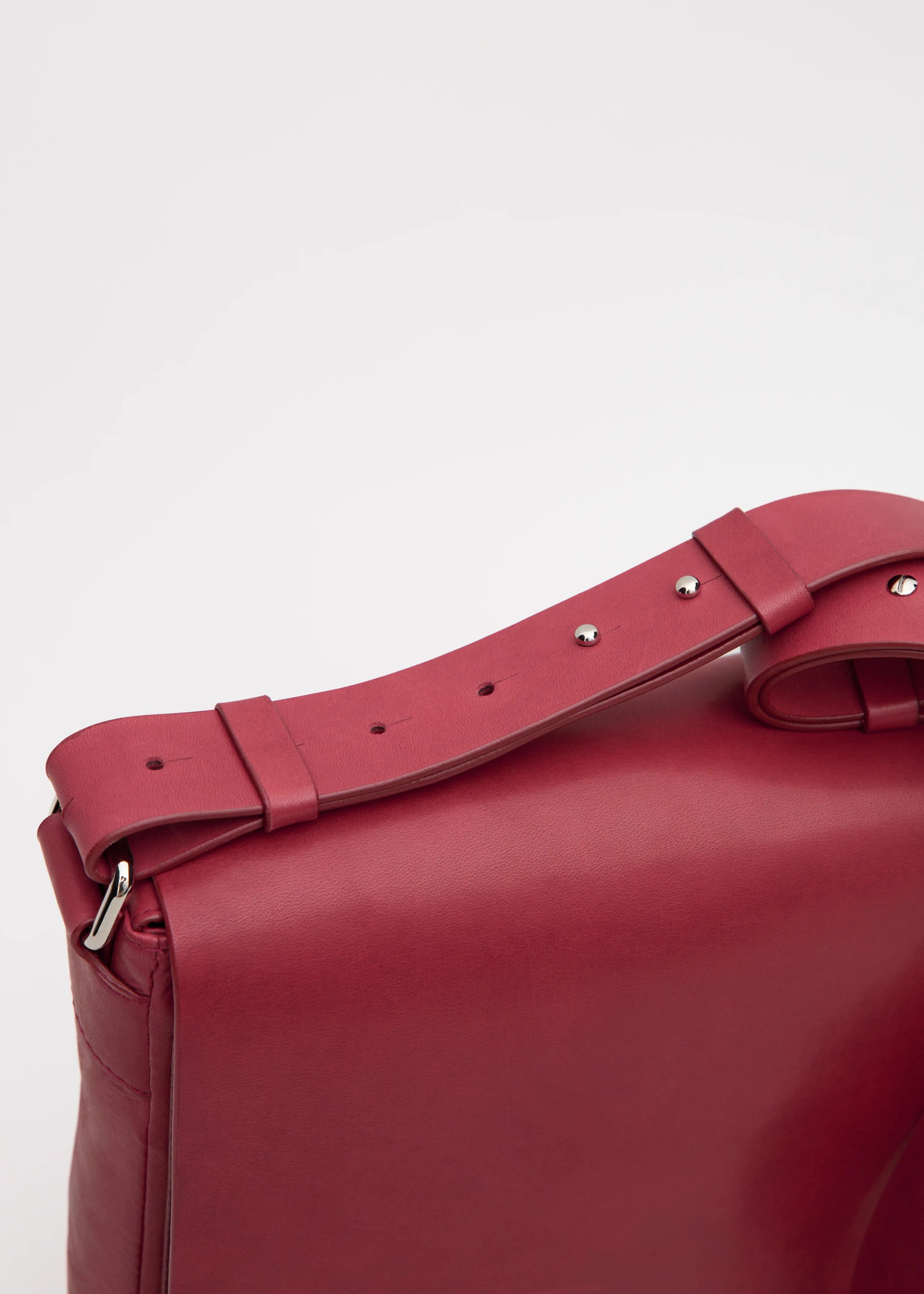 Close-up of the Philini Olga shoulder bag in red aniline nappa leather, showing the stamped logo, silver hardware attaching the leather strap.