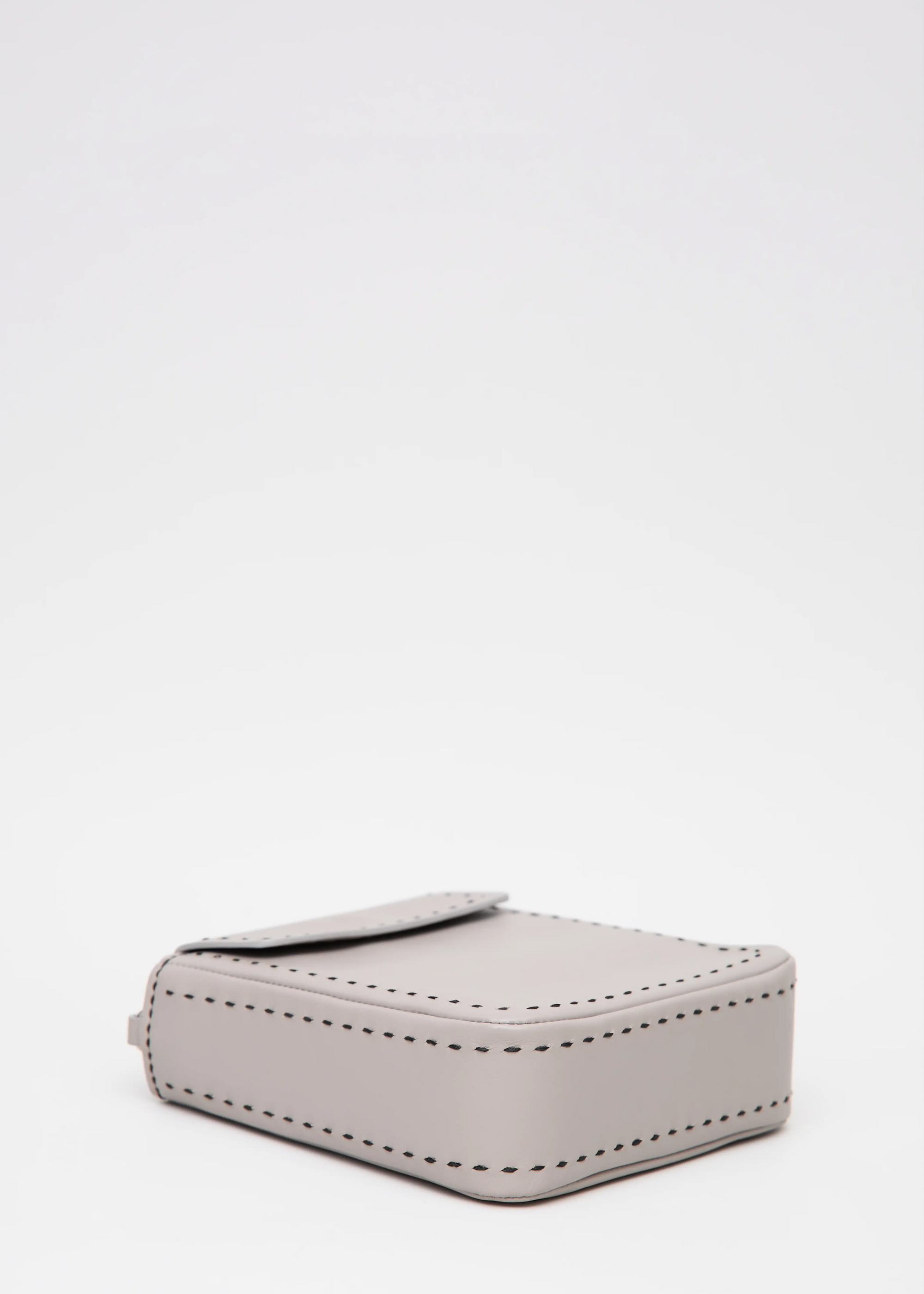 Laying Philini Saphira Purse in taupe aniline leather, compact rectangular shape with hand-stitched details, sleek half-lap flap, and convertible chain and leather straps. Elegant handmade leather evening purse.