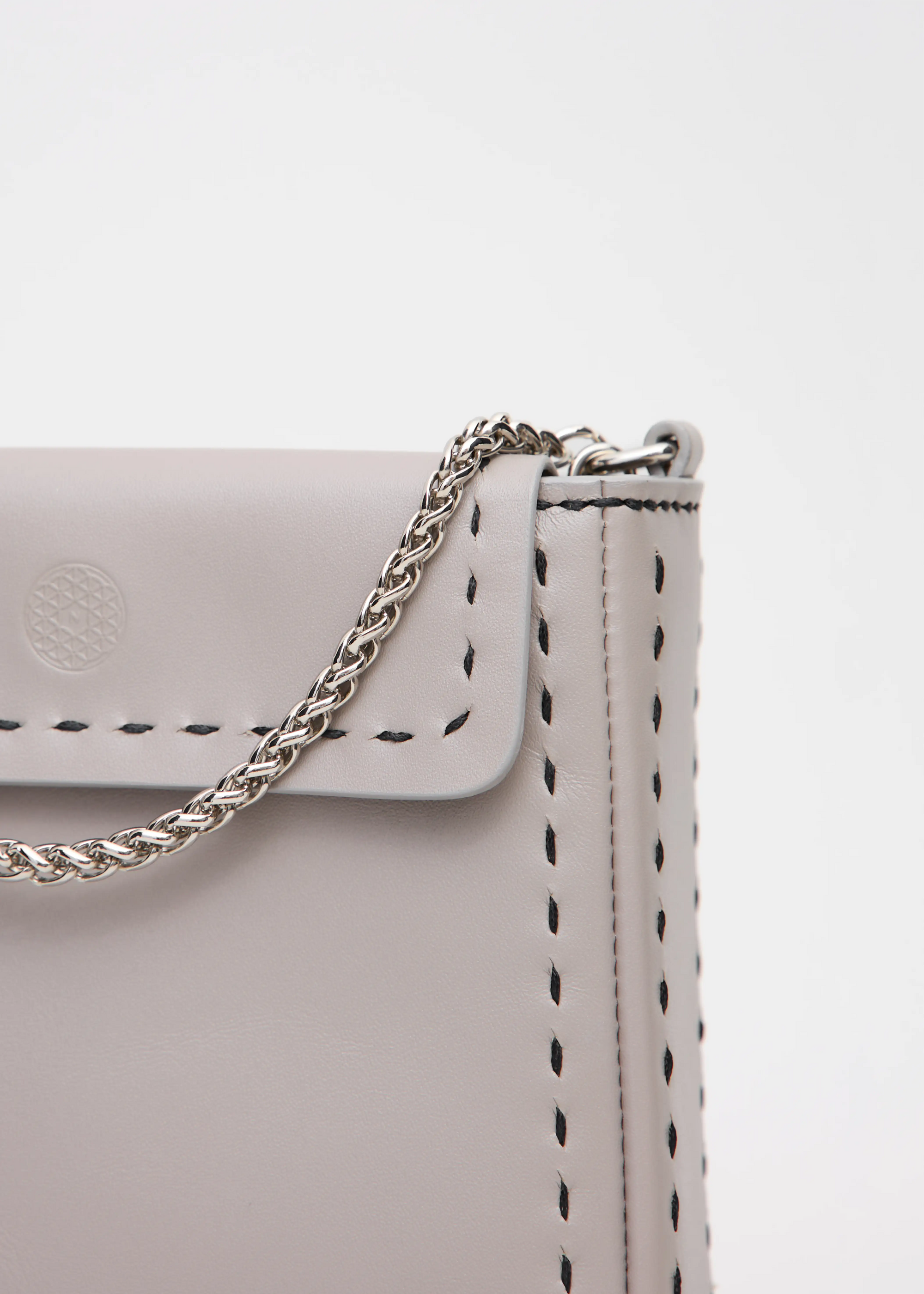 Detailed view of the Philini Saphira Purse in taupe aniline leather, compact rectangular shape with hand-stitched details, sleek half-lap flap, and convertible chain and leather straps. Elegant handmade leather evening purse.