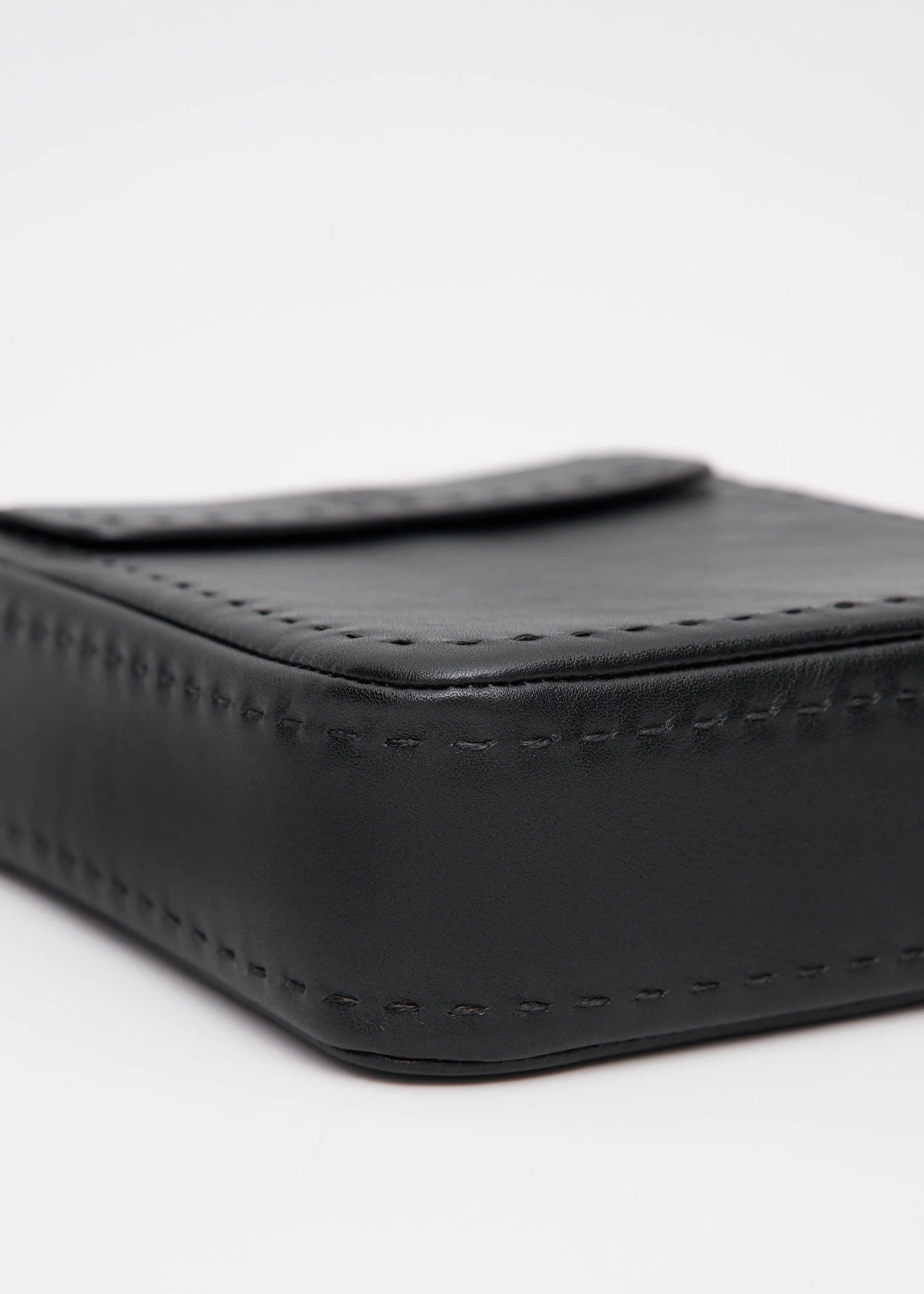 Bottom view of the Philini Saphira Purse in black aniline leather, compact rectangular silhouette with hand-stitched accents, smooth half-lap flap, and versatile leather and chain handles. Handmade black leather evening bag.